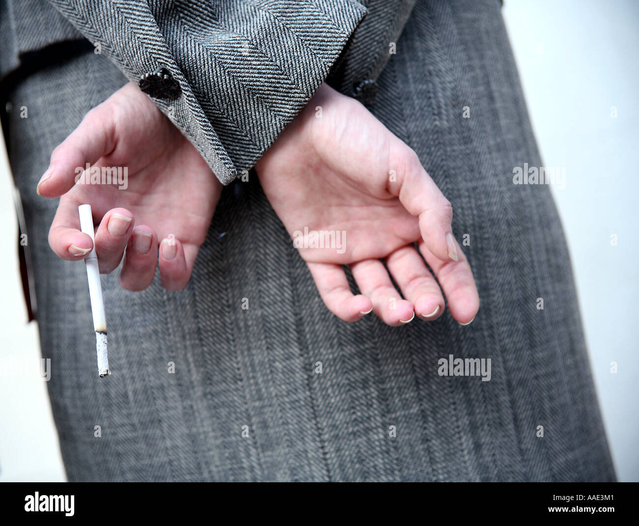 Smoker nascondendo la sua sigaretta dietro la schiena Foto Stock