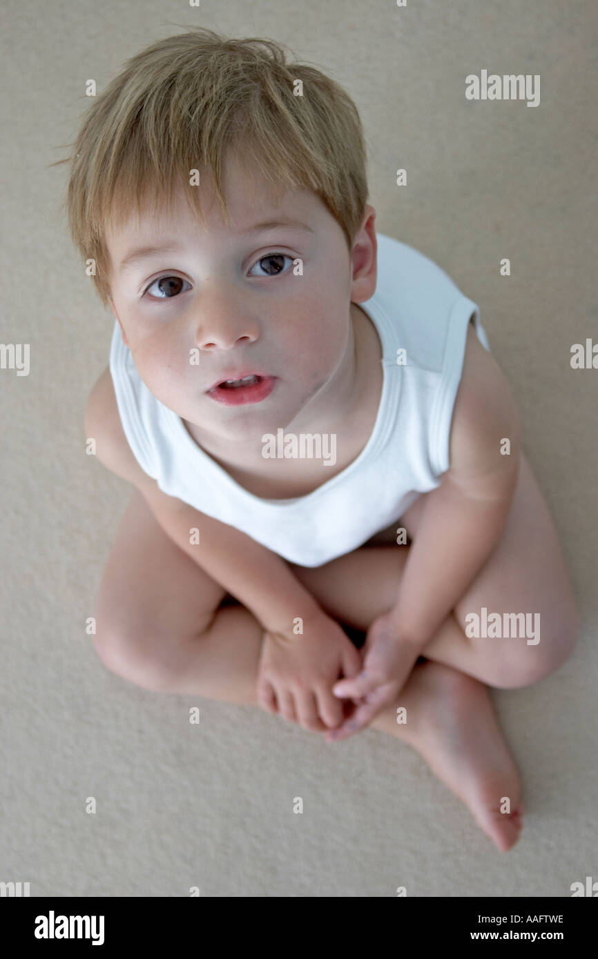 Ragazzo giovane bambino giubbotto in mutande e posa su un tappeto guardando dall'alto CJWH Foto Stock