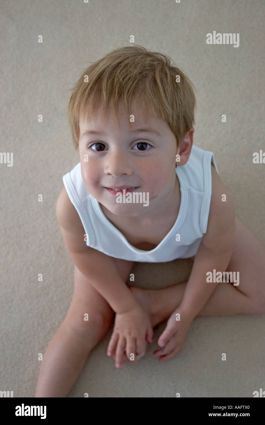 Ragazzo giovane bambino giubbotto in mutande e posa su un tappeto cercando sorridente dal di sopra CJWH Foto Stock