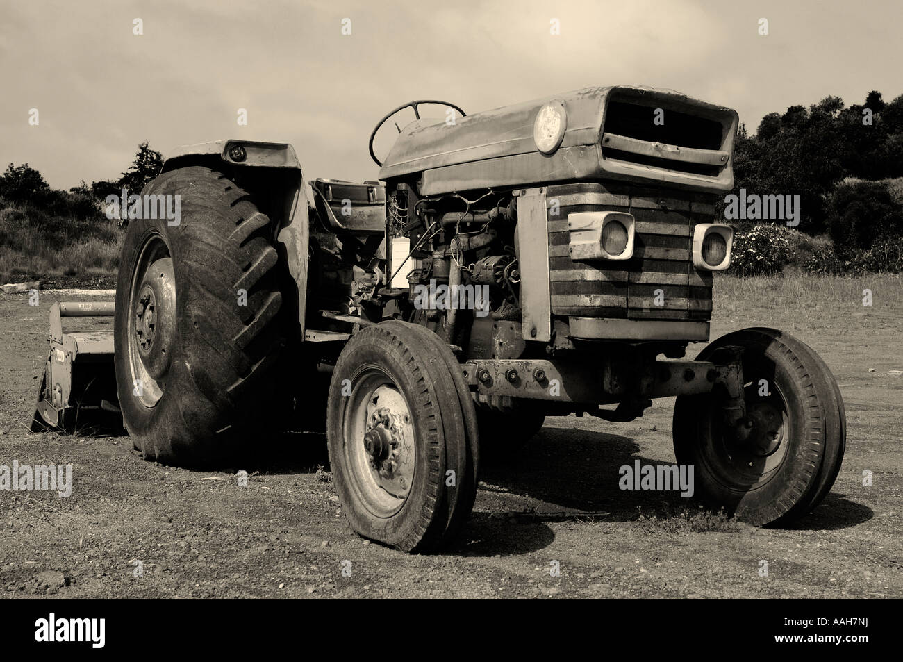 Il vecchio trattore arrugginito in un campo nero di seppia Foto Stock