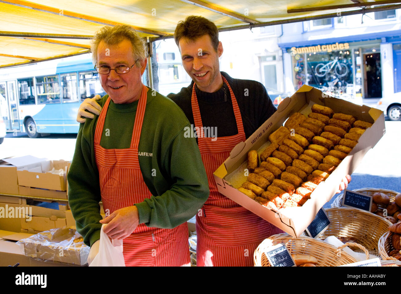 Due uomini in visita maschio del mercato francese di commercianti che vendono il bretone biscotti sul loro stallo in Aberystwyth Ceredigion nel Galles Foto Stock