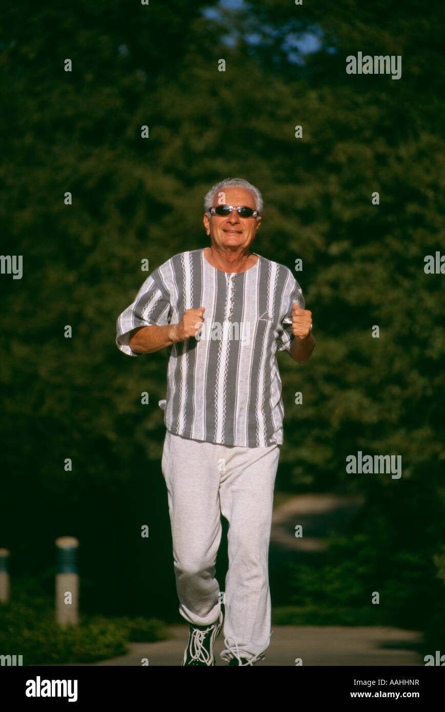 Un sorridente uomo anziano maschio senior 73 anni di esecuzione di esercizio Esercizio occhiali da sole Occhiali da sole nel parco verde spazio copia POV SIGNOR ©Myrleen Pearson Foto Stock