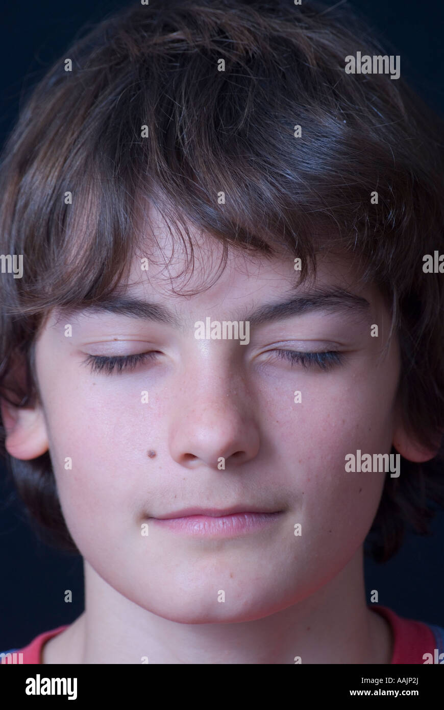 Un ragazzo di 15 anni con gli occhi chiusi come se stesse meditando Foto Stock