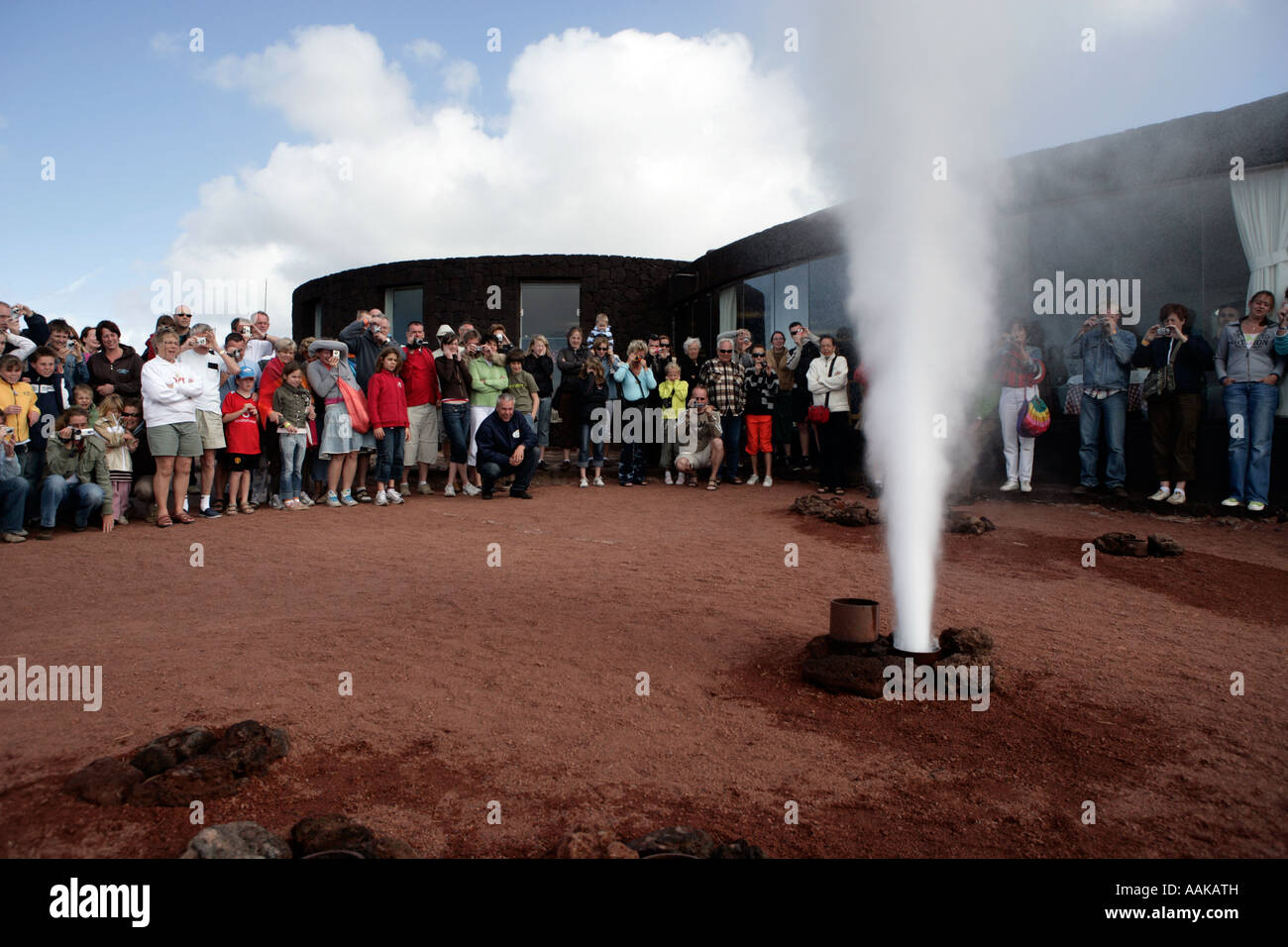 I turisti guardare geyser di acqua e vapore sparare da terra a Timanfaya Montagna di Fuoco Foto Stock