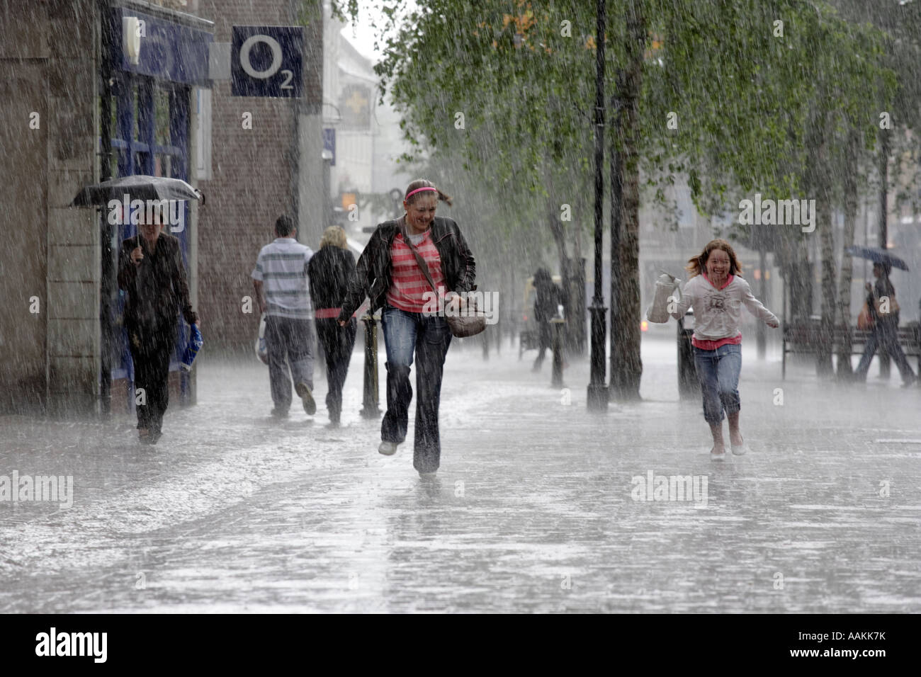 Due bambini catturati in una tempesta di pioggia corrono verso la high street di Bromsgrove in WORCESTERSHIRE REGNO UNITO Foto Stock