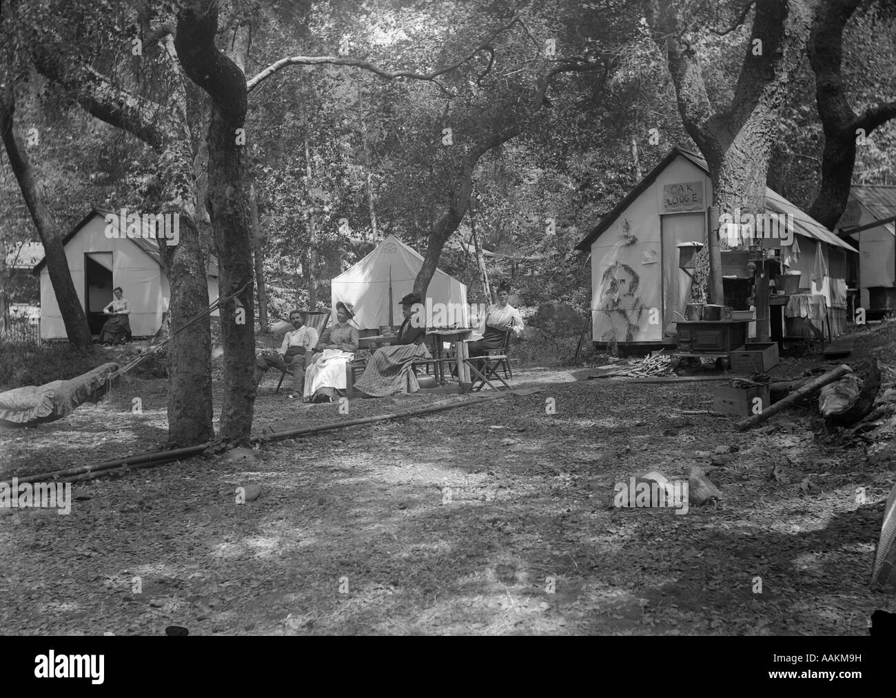 1900s 1910s gruppo seduto fuori la tenda e cabine in campeggio Foto Stock