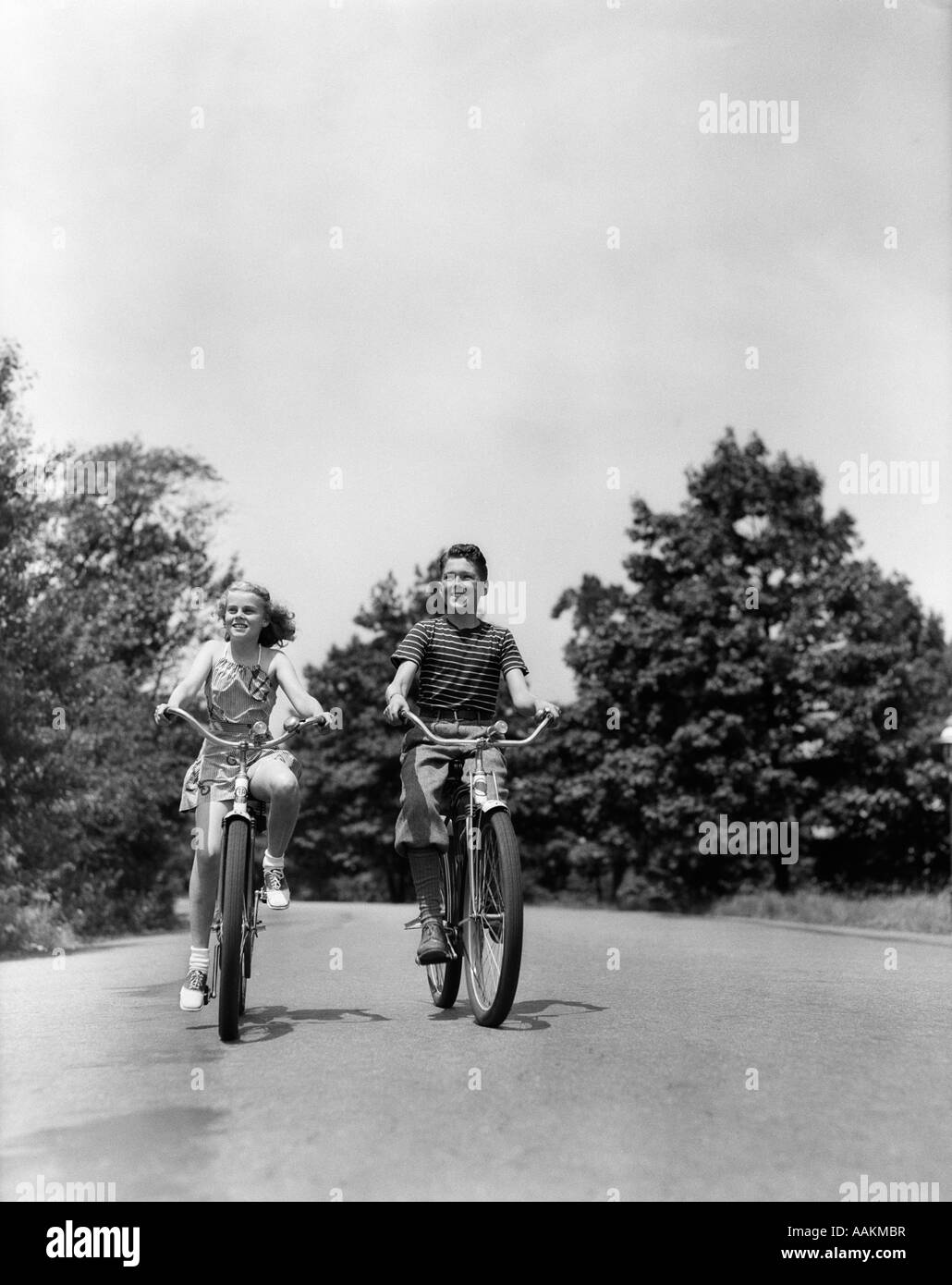 1940s BOY GIRL equitazione biciclette paese giù LANE Foto Stock