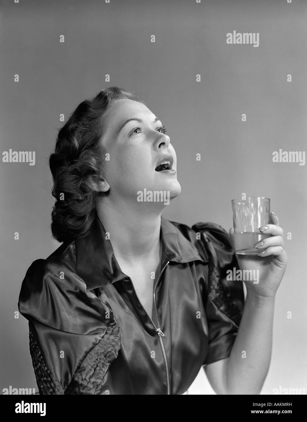 1940s BRUNETTE donna tenere il vetro GARGARISMI GARGLING BOCCA APERTA LA TESTA INDIETRO mal di gola alito cattivo medicina di collutorio Foto Stock