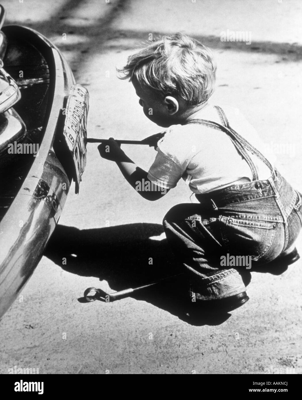 Anni Cinquanta TODDLER BOY giocando a riparazione auto rimozione TARGA CON CACCIAVITE Foto Stock