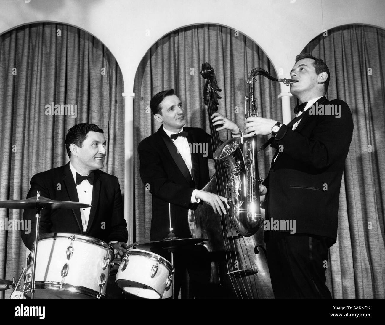 Anni Cinquanta TRE UOMINI IN TUXEDOS TRIO MUSICALE CON TAMBURI VERTICALE DI BASE E Sassofono Foto Stock