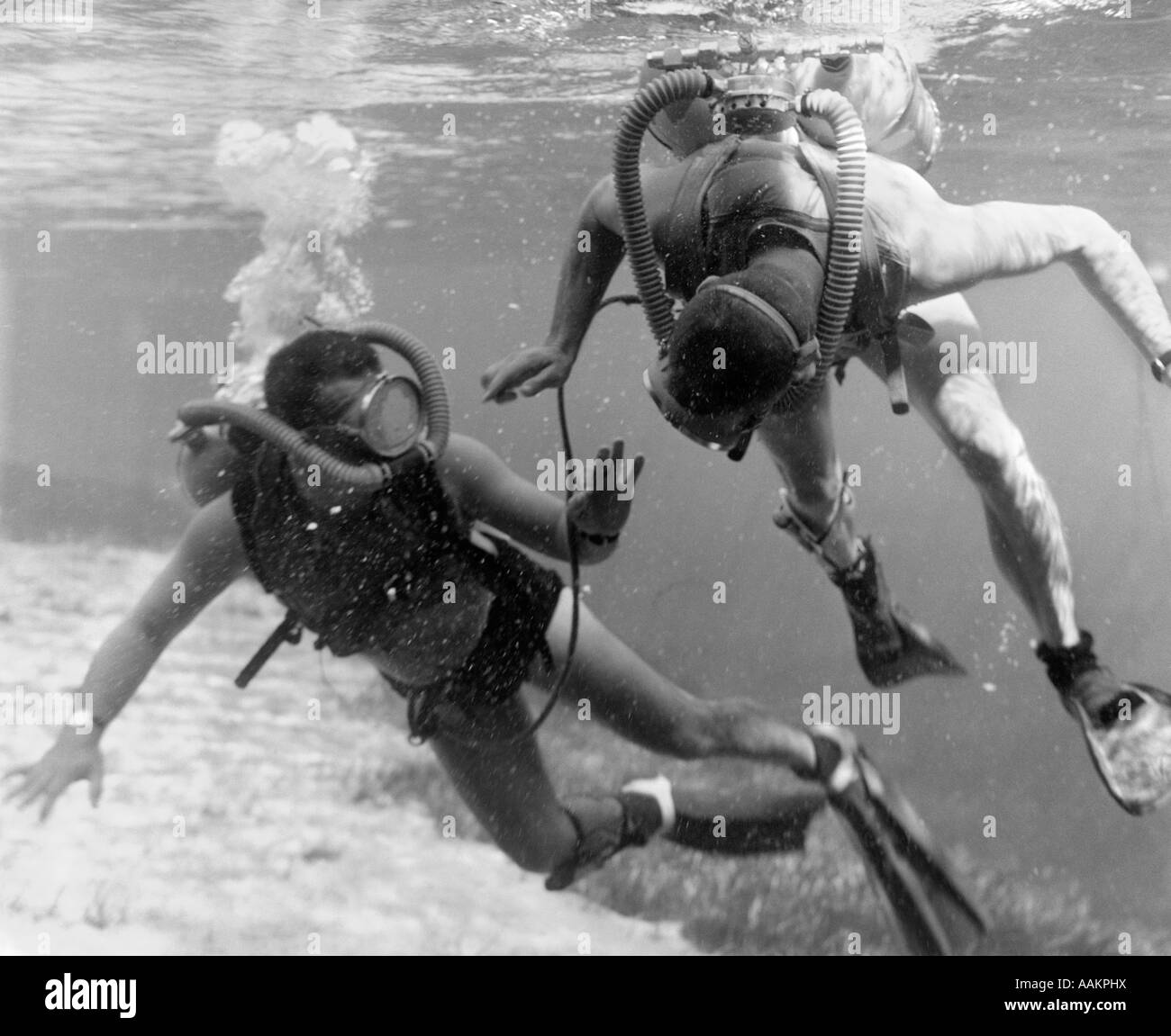 Anni sessanta COPPIA DI subacquei con vasche e maschere in acque poco profonde vicino area erbosa dell oceano pavimento Foto Stock