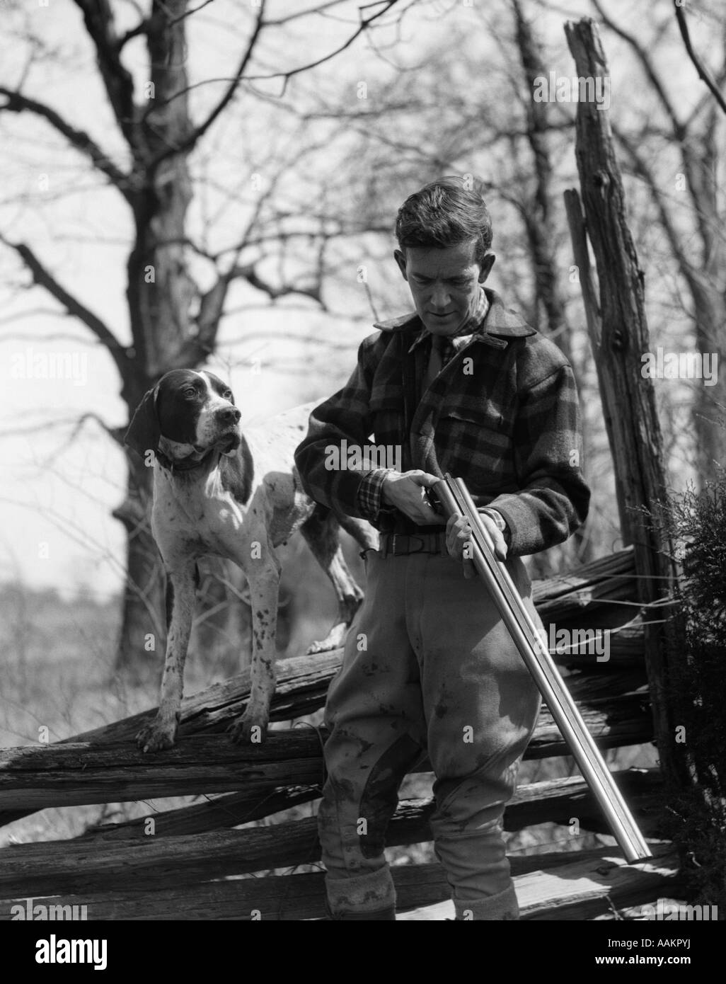 1930 L'uomo uccello HUNTER HOLDING DOUBLE BARREL SHOTGUN gusci di caricamento con il suo cane di puntatore in piedi su un gruppo spintore a rampa Foto Stock