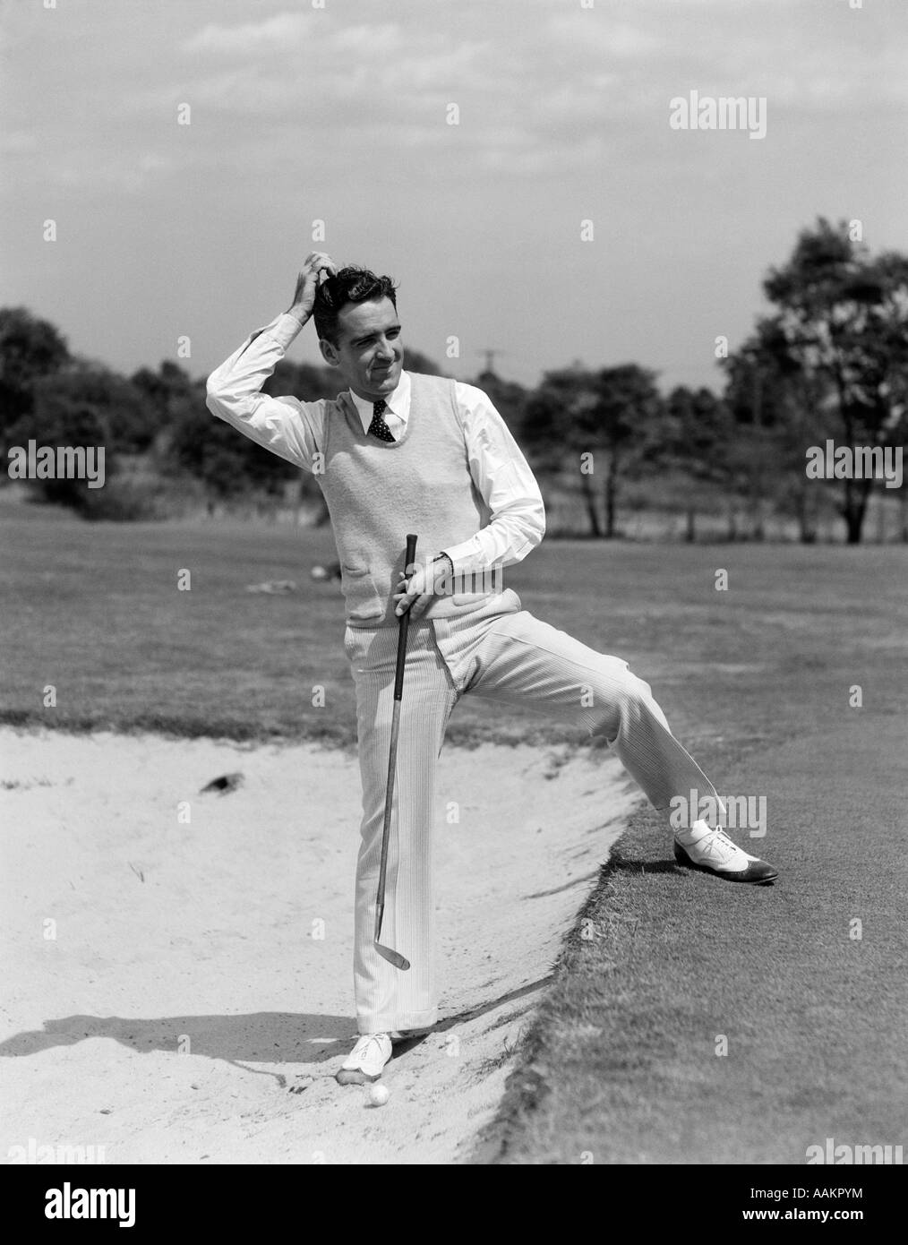 1930s uomo golfista sabbia trappola di graffiare la sua testa Foto Stock