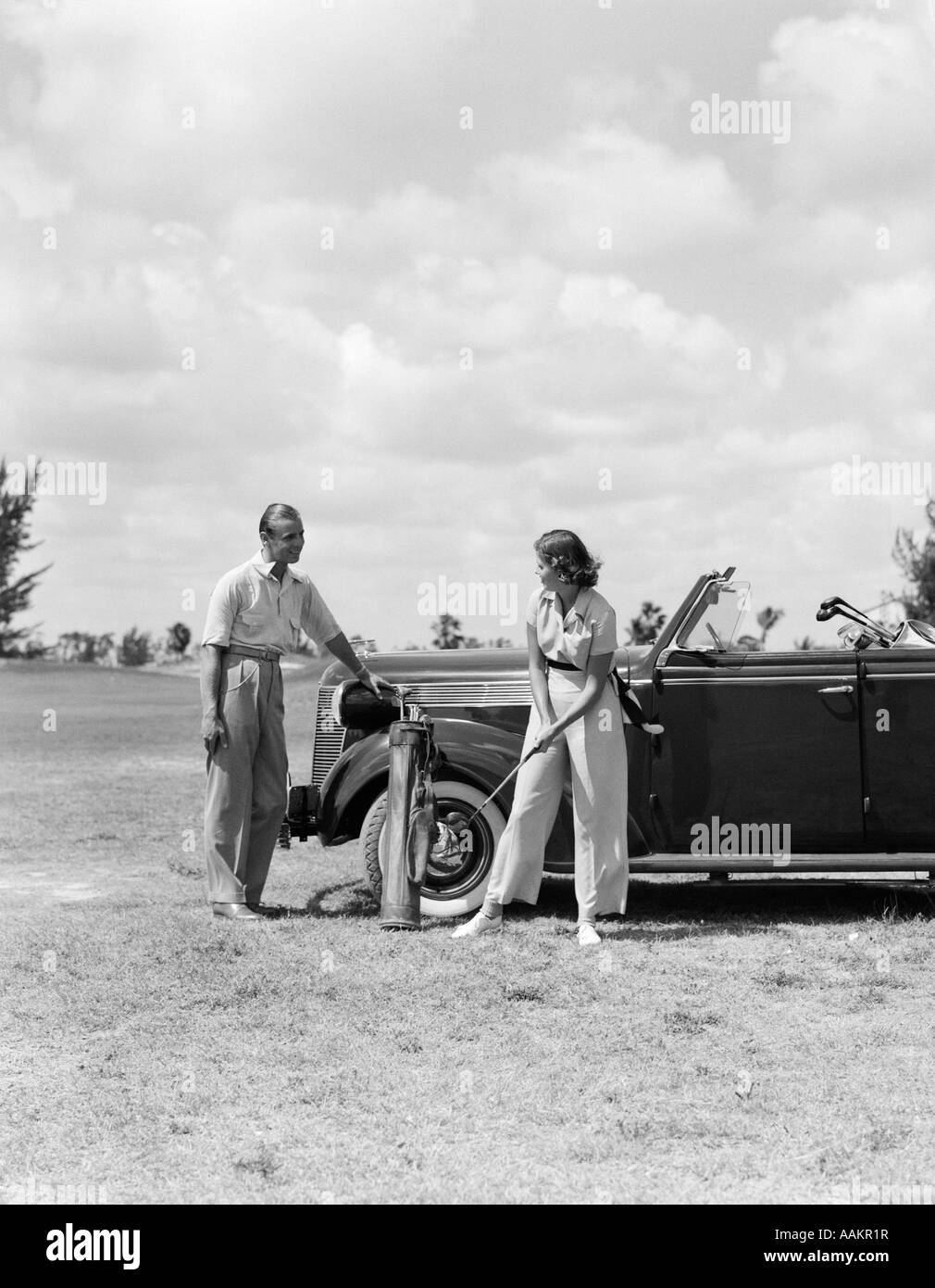 Negli anni trenta i golfisti giovane uomo donna accanto a AUTO Foto Stock