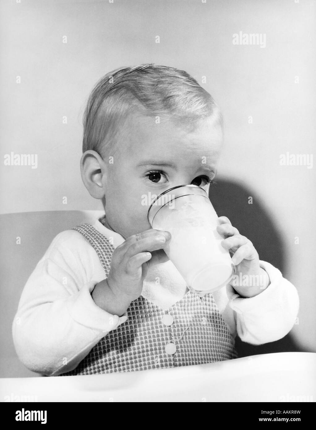 Anni Cinquanta BOY bimbo a bere latte vetro guardando la fotocamera Foto Stock
