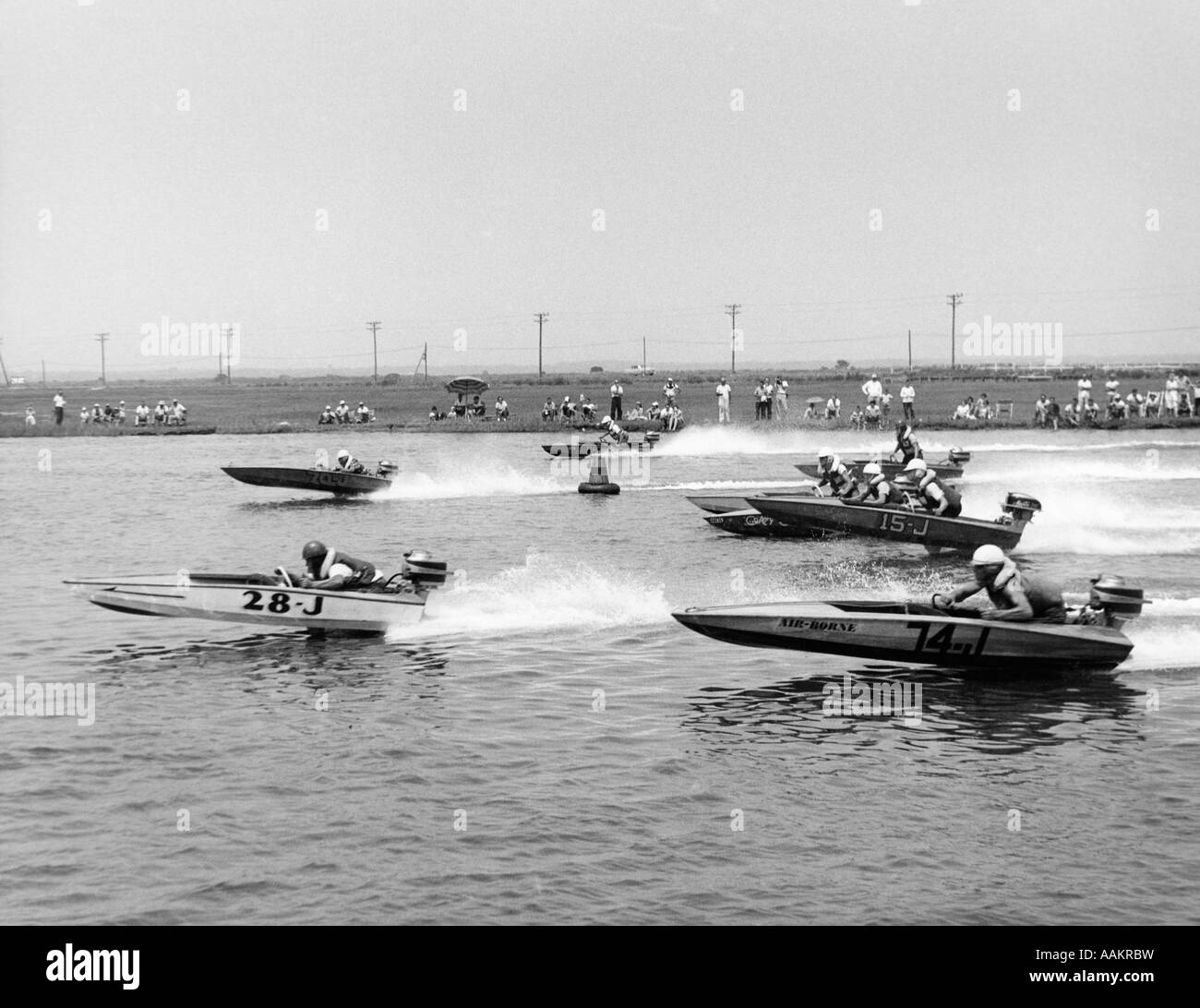 Degli anni Cinquanta VISTA LATERALE DI SPEEDBOAT GARA CON GLI SPETTATORI in piedi sulla riva IN BACKGROUND Foto Stock