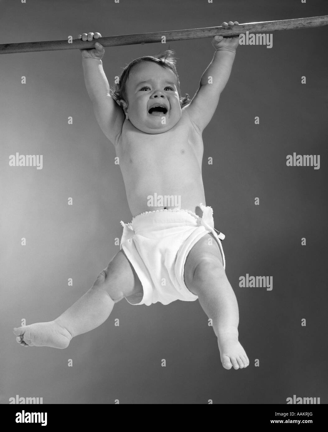 Anni sessanta BABY sospesi da asta con espressione spaventata sul punto di piangere Foto Stock