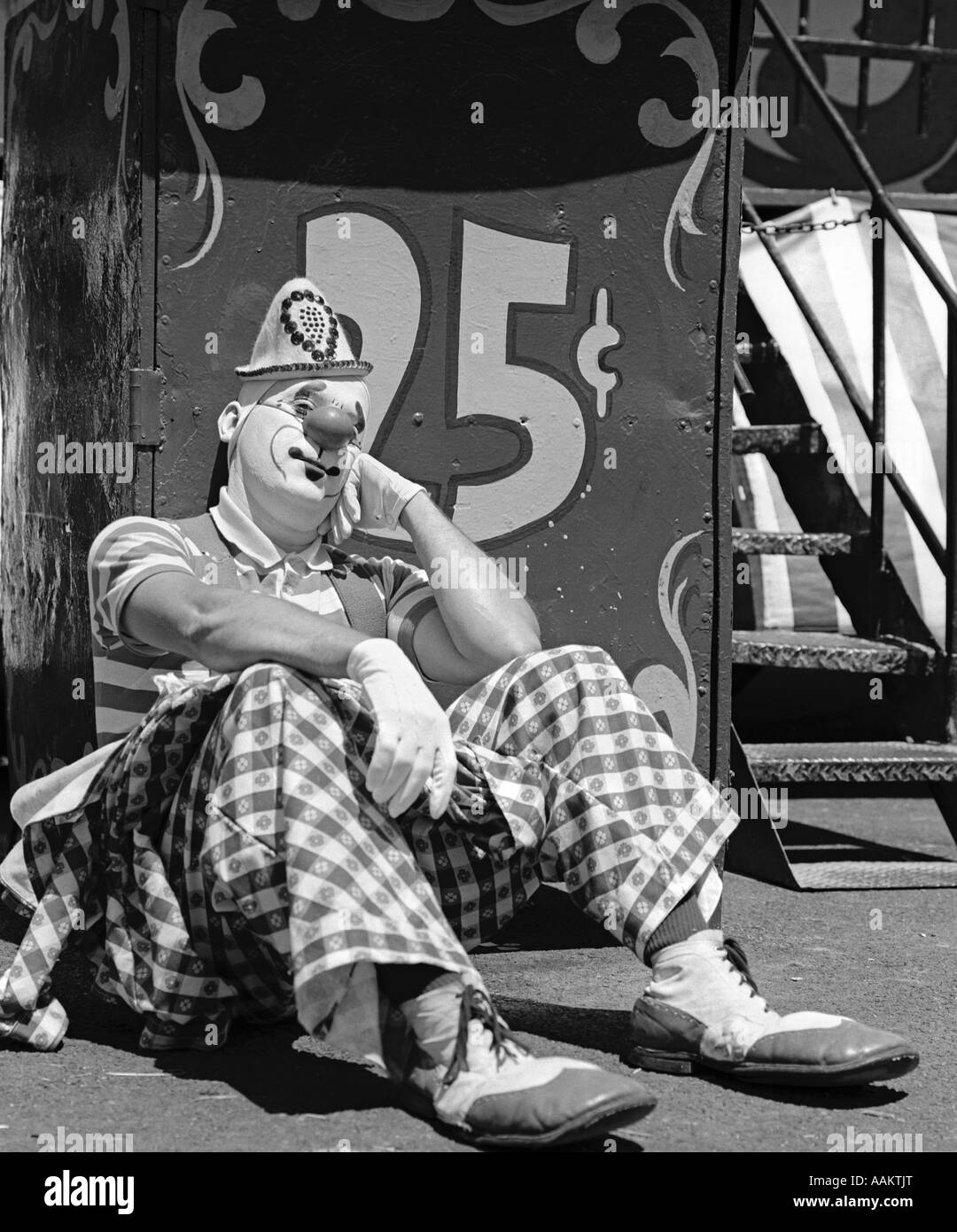 Anni Settanta triste clown seduto appoggiato la guancia sulla mano appoggiata sulla lettura stand 25 centesimi Foto Stock