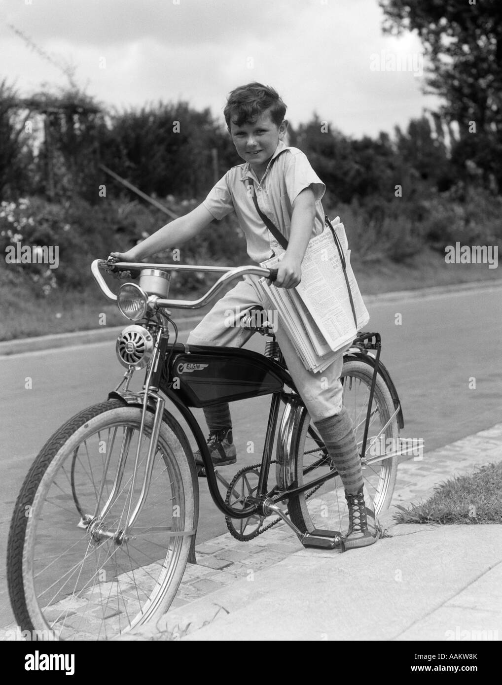 1940s ragazzo in un Elgin BIKE portando quotidiani in una imbracatura ginocchio Indossare calzini e scarpe da ginnastica Foto Stock
