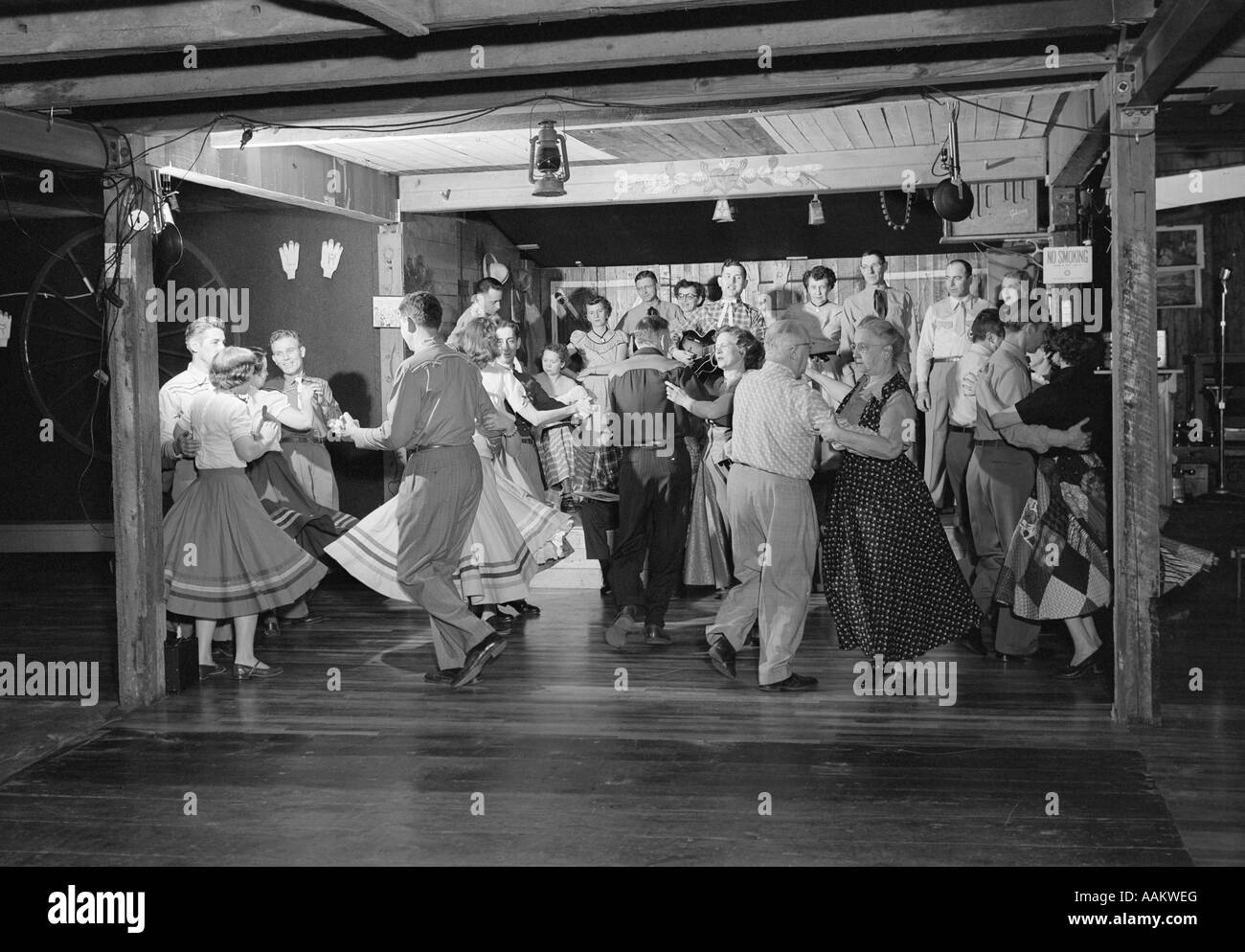 Anni Cinquanta ballerini quadrato IN COUNTRY WESTERN OUTFITS ballare con la musica di una piccola band in un granaio Foto Stock