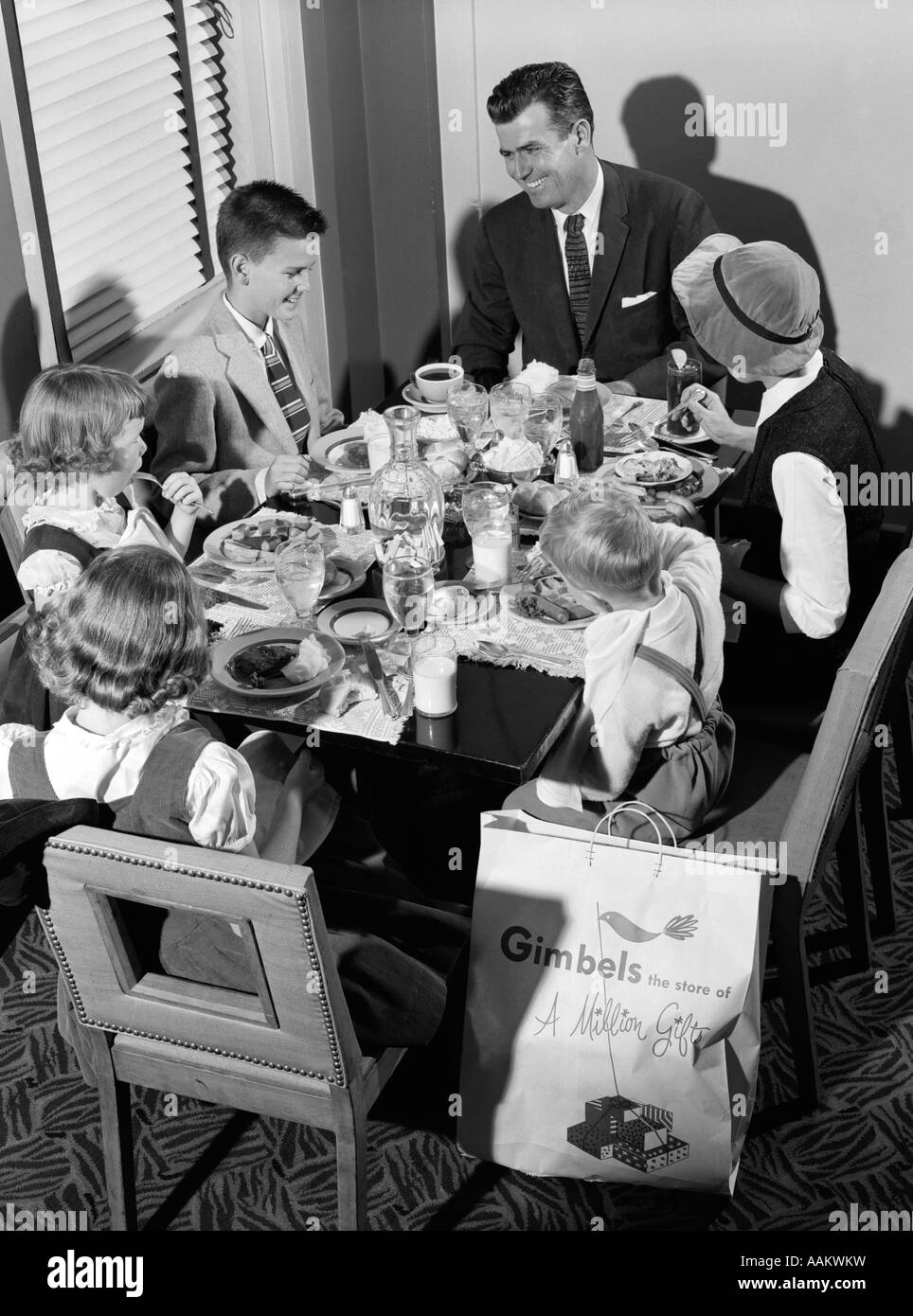 Degli anni Cinquanta la famiglia di sei a mangiare in un ristorante mentre fuori shopping Foto Stock
