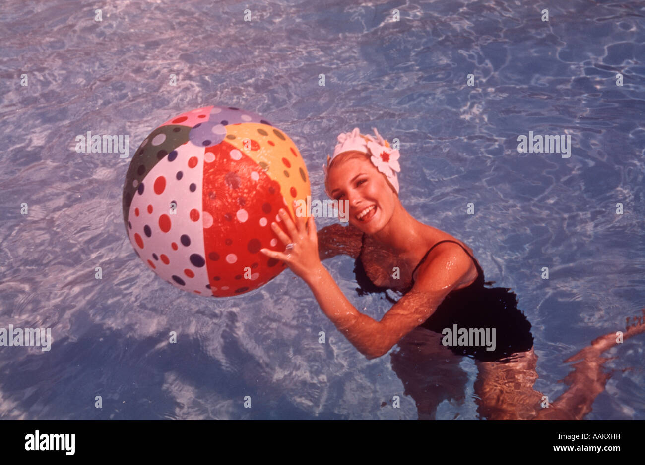 Anni sessanta DONNA IN PISCINA tenendo palla spiaggia Foto Stock