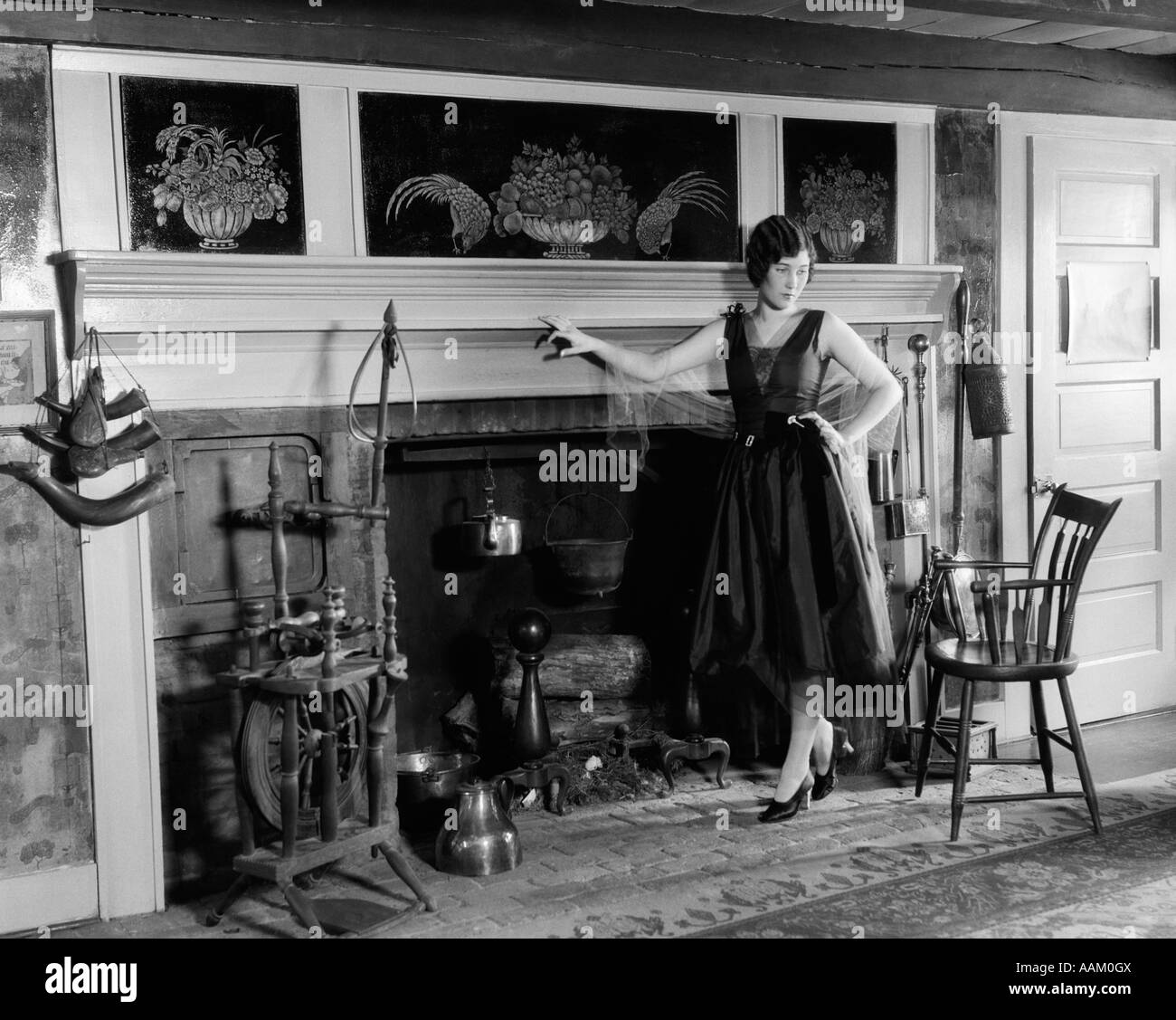 1920s donna in abito da cocktail in piedi di fronte a un grande caminetto Foto Stock