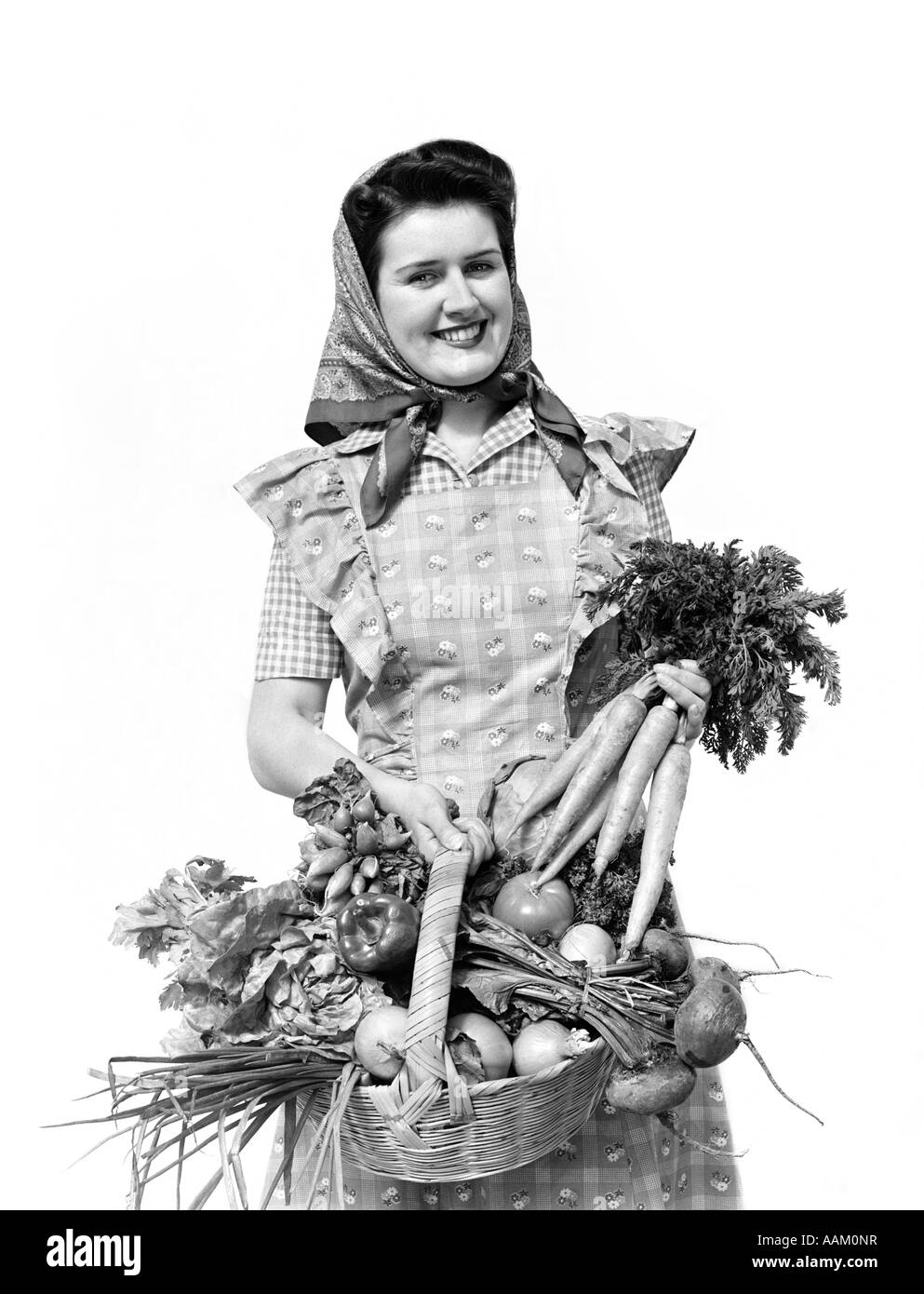 1940s donna ritratto AL TRASPORTO DELLA FOTOCAMERA cesto pieno di ortaggi di giardino guardando la fotocamera Foto Stock