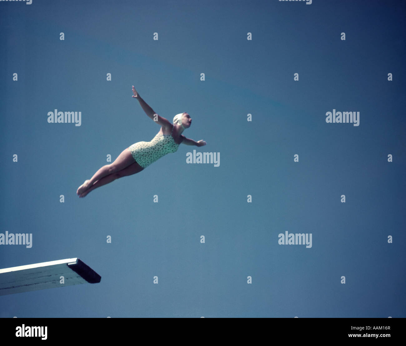 Anni Cinquanta donna che indossa uno bianco PEZZO COSTUME E CAPPUCCIO SWAN centro immersioni di alto bordo contro il cielo blu Foto Stock