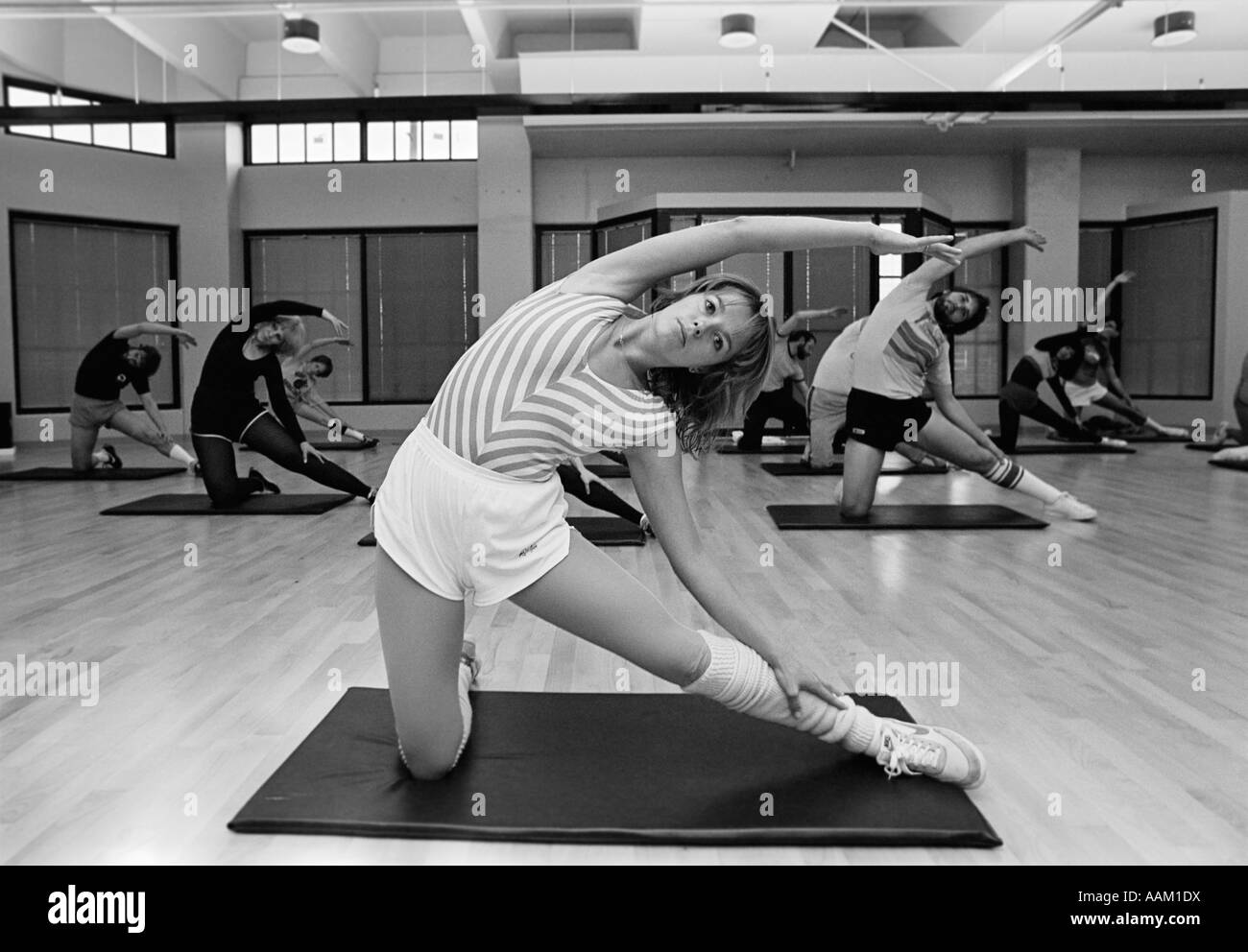 Negli anni ottanta la classe di aerobica OGNI PERSONA SU UN SINGOLO MAT STRETCHING guardando la fotocamera Foto Stock