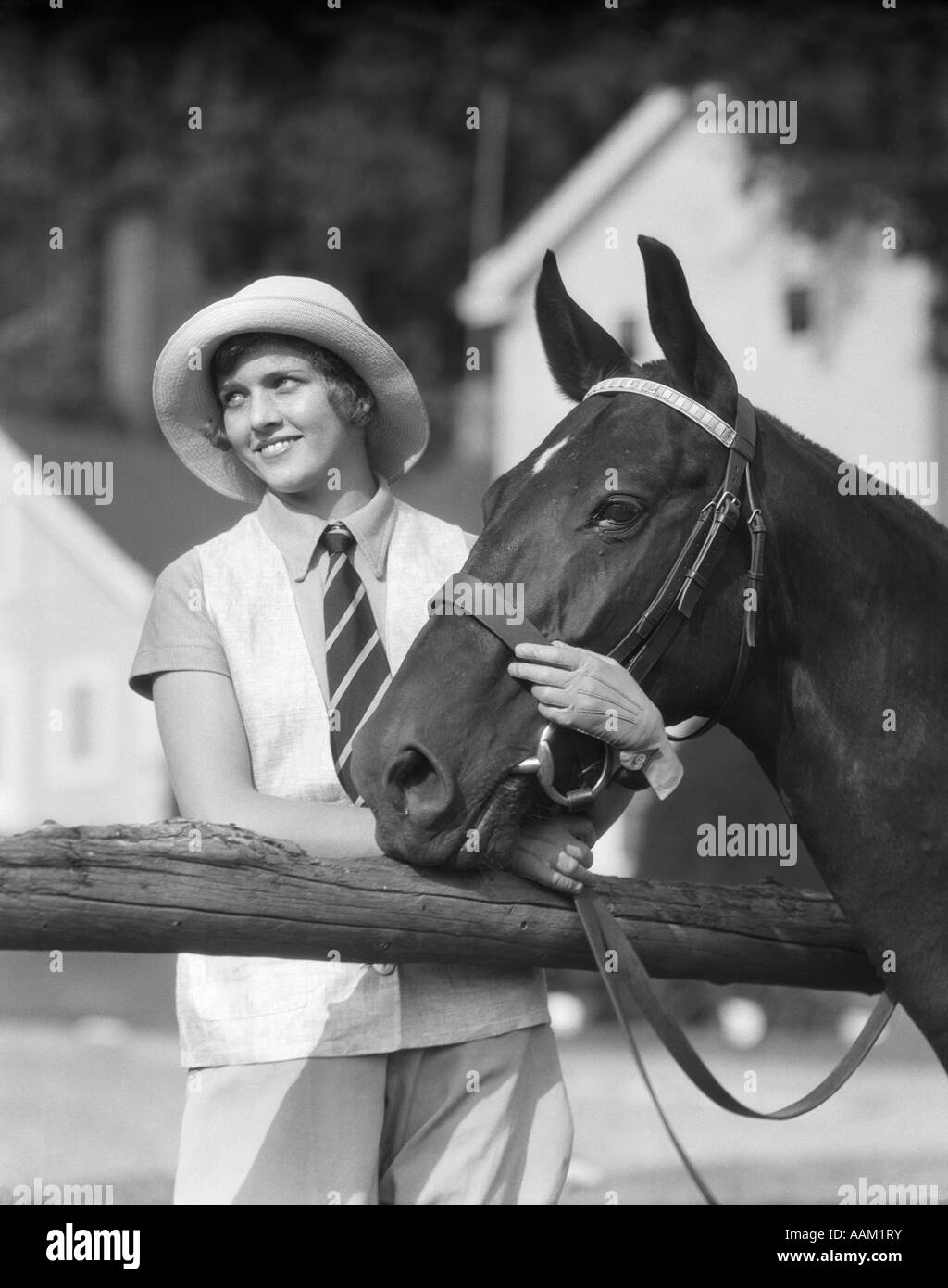 1930s WOMAN IN HAT sorridente guardando accanto a strisce che indossa cravatta HOLDING REDINI E CAVALLI TESTA CACCIATORE SNAFFLE BRIGLIA Foto Stock