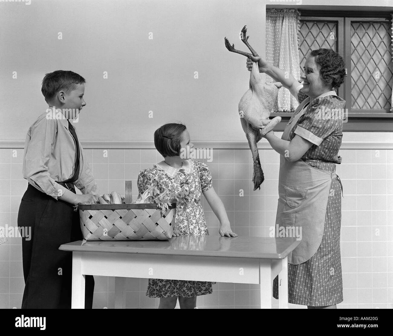 1940s casalinga che mostra crudo fresco strappato alla Turchia di figlio e figlia IN CUCINA Foto Stock