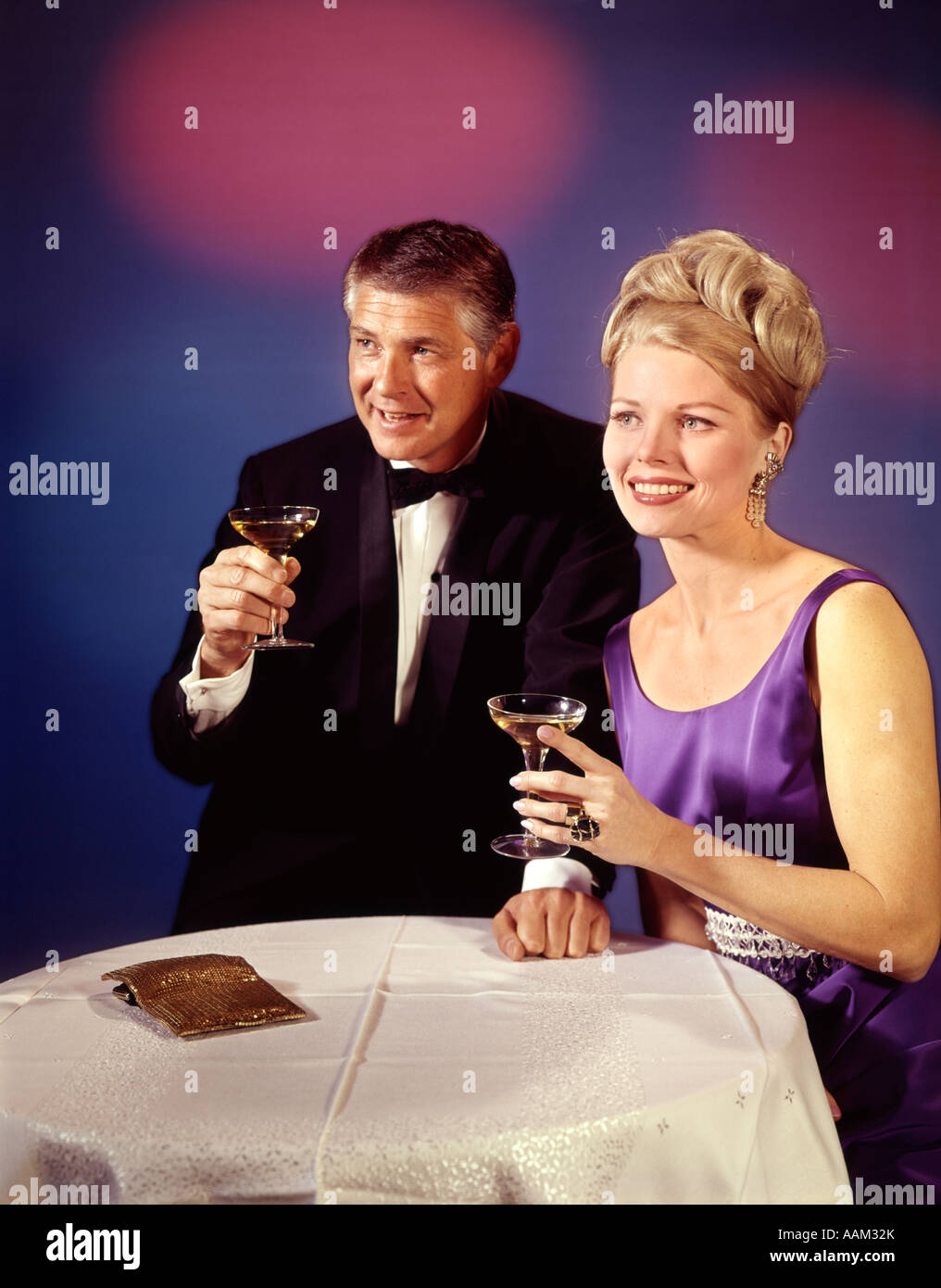 Anni sessanta anni settanta GIOVANE UOMO E DONNA IN SMOKING FORMALE E ABITO  DA SERA tostatura sorridente con bicchieri di champagne Foto stock - Alamy