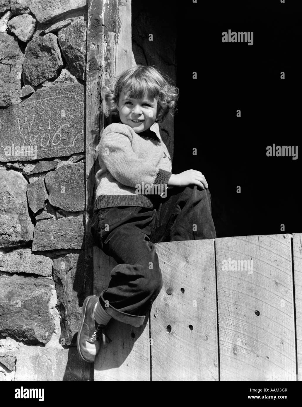 Negli anni quaranta anni cinquanta sorridente ragazza indossare pantaloni FELPA CON SEDUTA IN LEGNO PIETRA PORTA FARM BARN COSTRUITO NEL 1806 Foto Stock