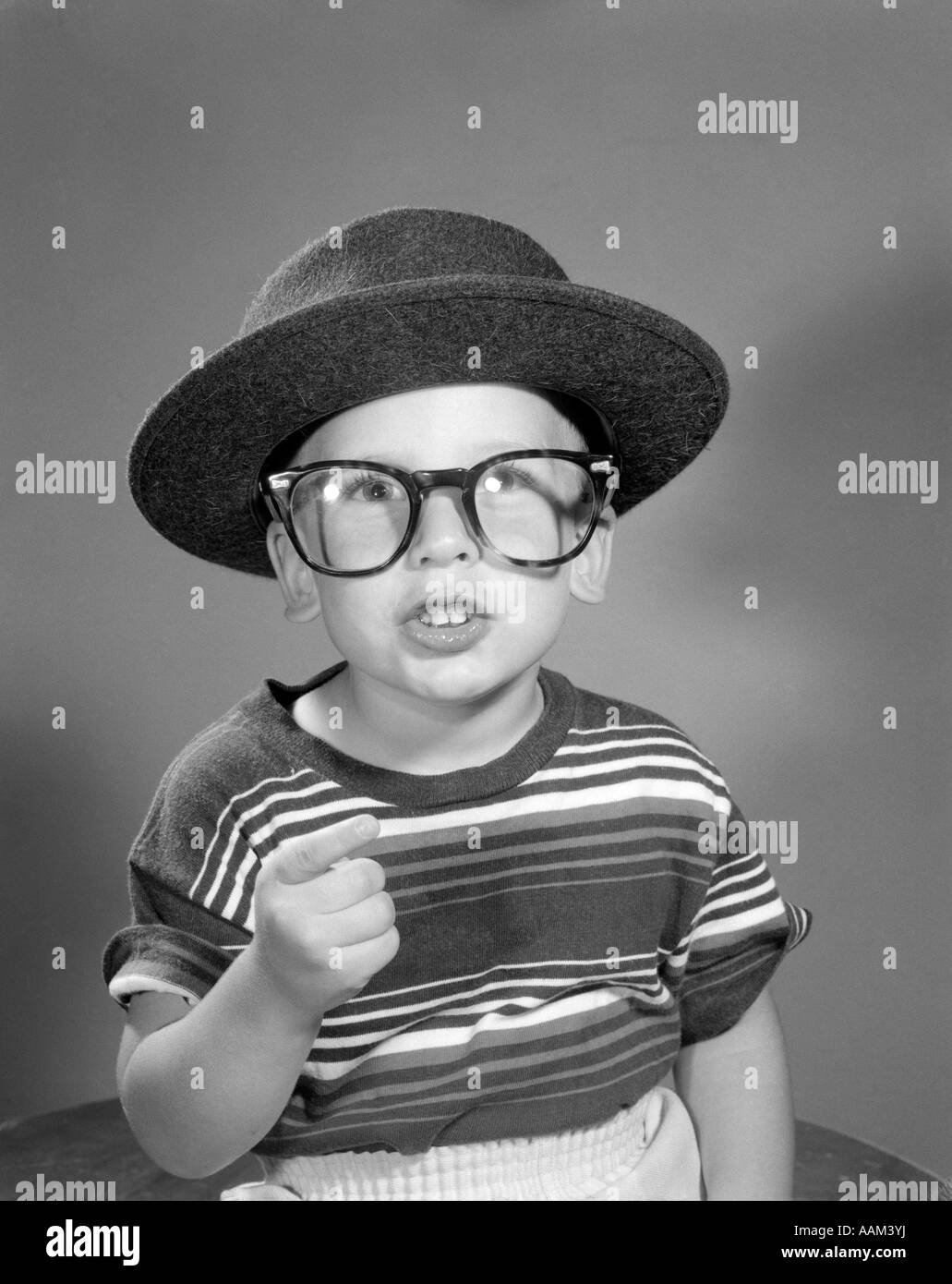 Anni Cinquanta ritratto ragazzo vestirsi in adulto uomo d affari del cappello e occhiali indossando STRIPED TEE SHIRT Foto Stock