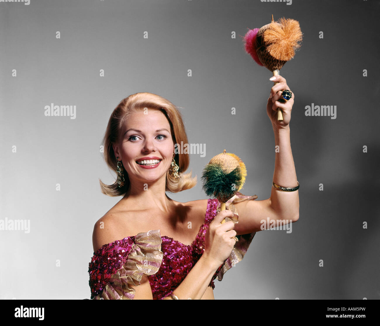 Anni sessanta anni settanta DONNA BIONDA ARRUFFATA HALTER TOP sorridente latino musica agitando le Maracas Foto Stock