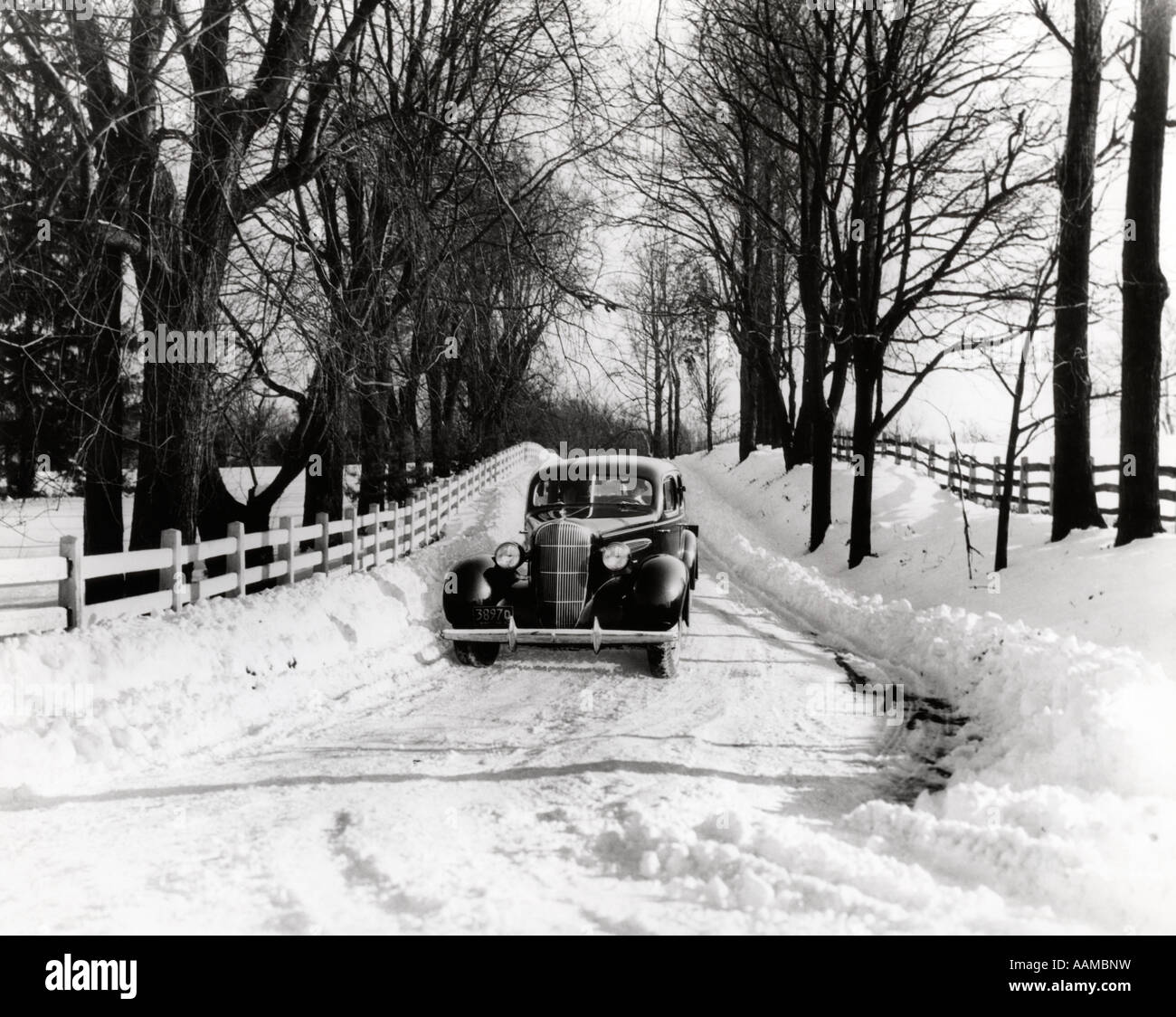 1930s auto guidando verso il basso SNOWY COUNTRY ROAD Foto Stock