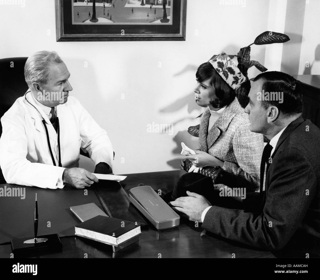 Anni sessanta uomo anziano MEDICO IN UFFICIO AVENTE LA DISCUSSIONE CON IL MARITO E LA MOGLIE INDOOR Foto Stock