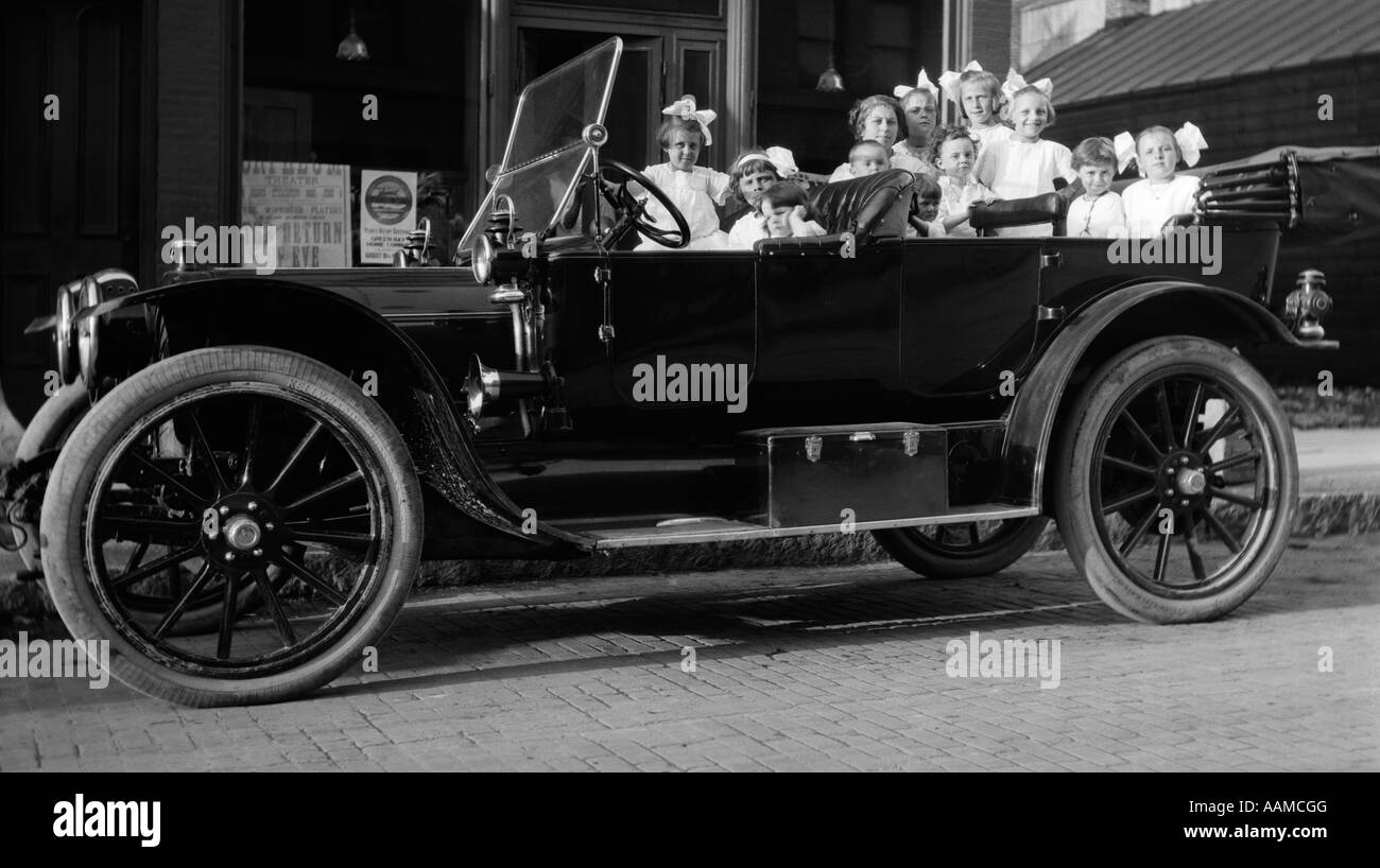 1910s 1920s grande gruppo di bambine in abiti bianchi impaccato in un convertibile parcheggiata TOURING AUTOMOBILE Foto Stock