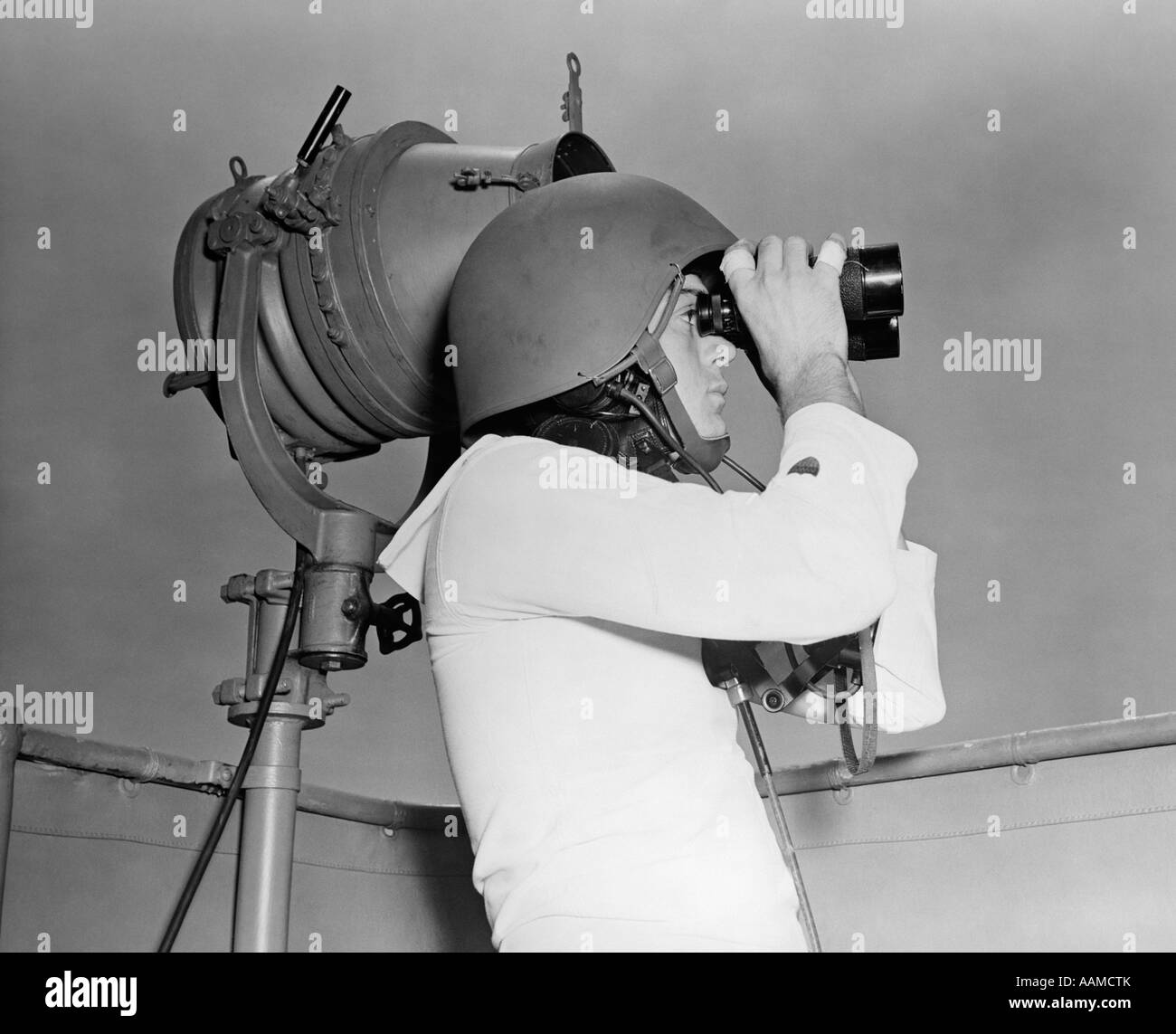 1940s WWII VINTAGE SAILOR bianco uniforme casco impugnare il binocolo in piedi accanto a intermittenza della spia del messaggio Foto Stock