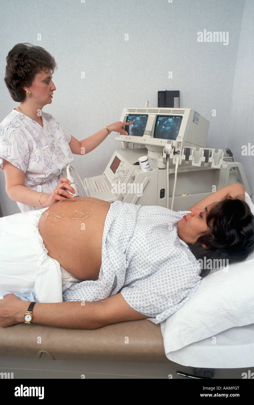 Giovane madre di essere guarda a schermo durante la procedura di ultrasuoni Foto Stock