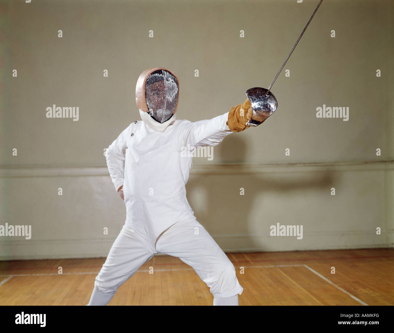 Anni sessanta uomo usura imbottita bianco recinzioni protettive per ingranaggi e casco allungandoti in telecamera LUNGE EN GARDE EPEE SPADA Foto Stock