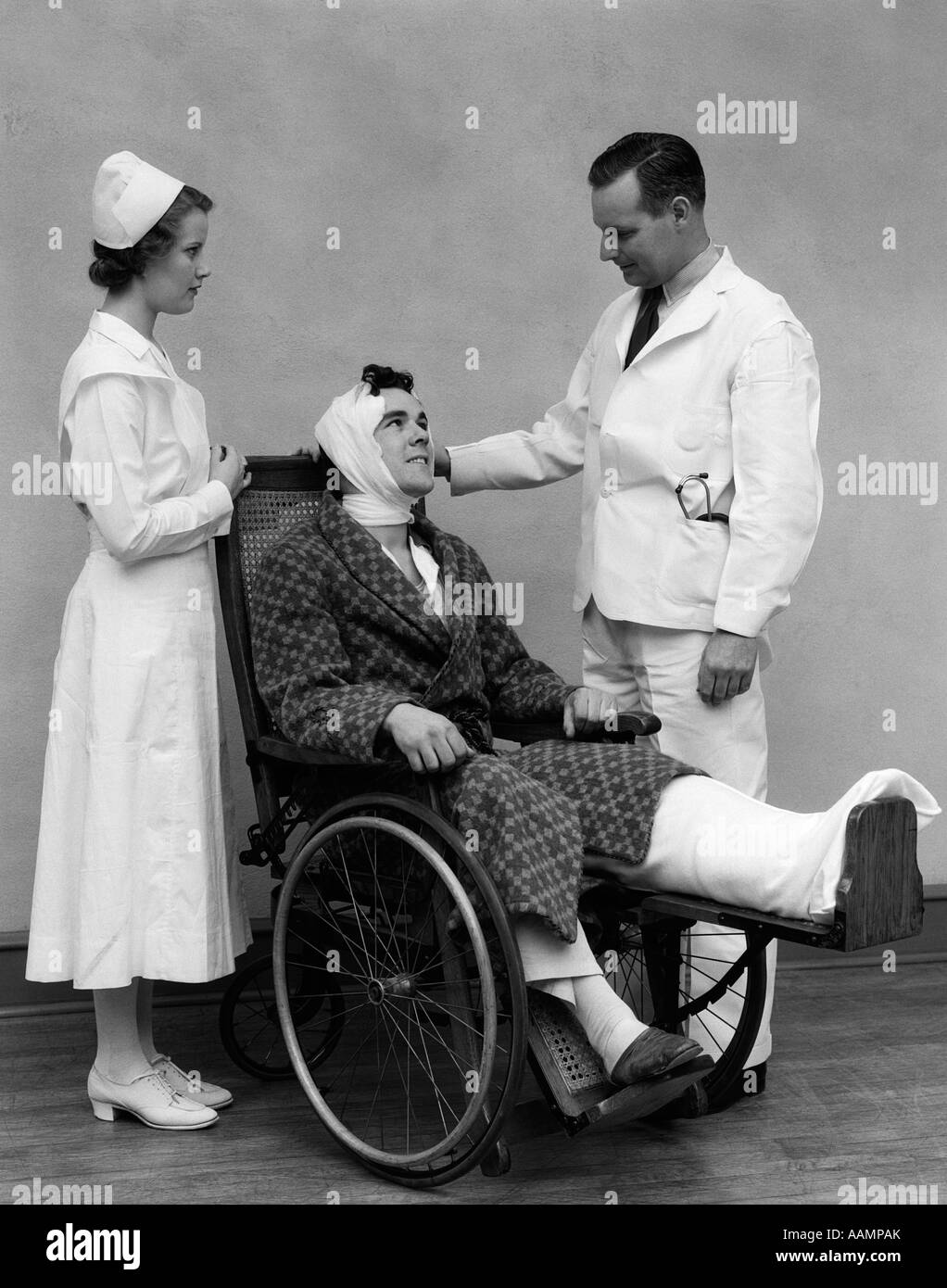 1930s medico infermiere e uomo in sedia a rotelle con la testa fasciata e piedi Foto Stock