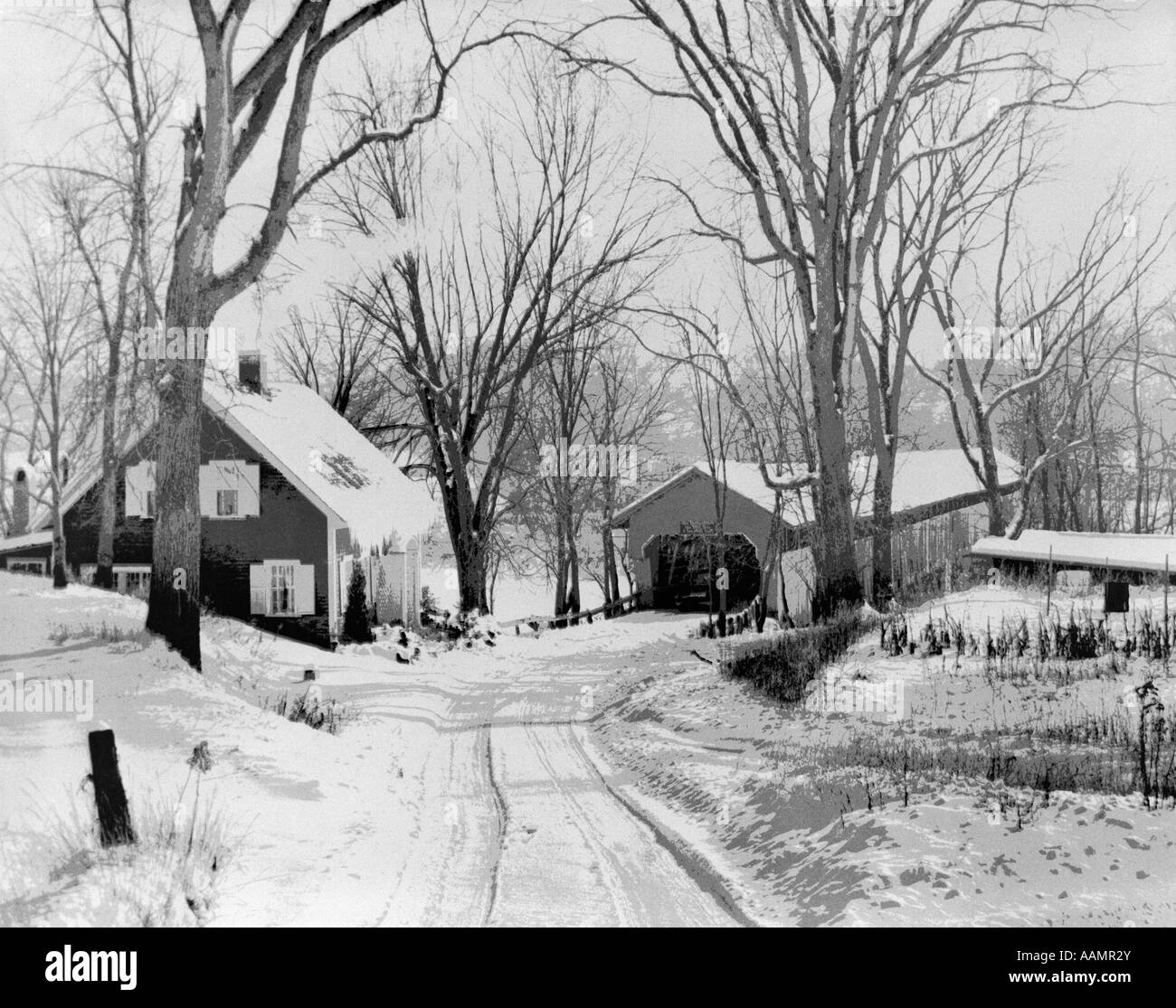 Anni Cinquanta inverno strada che conduce al ponte coperto e casa freddo innevato paesaggio rurale Foto Stock