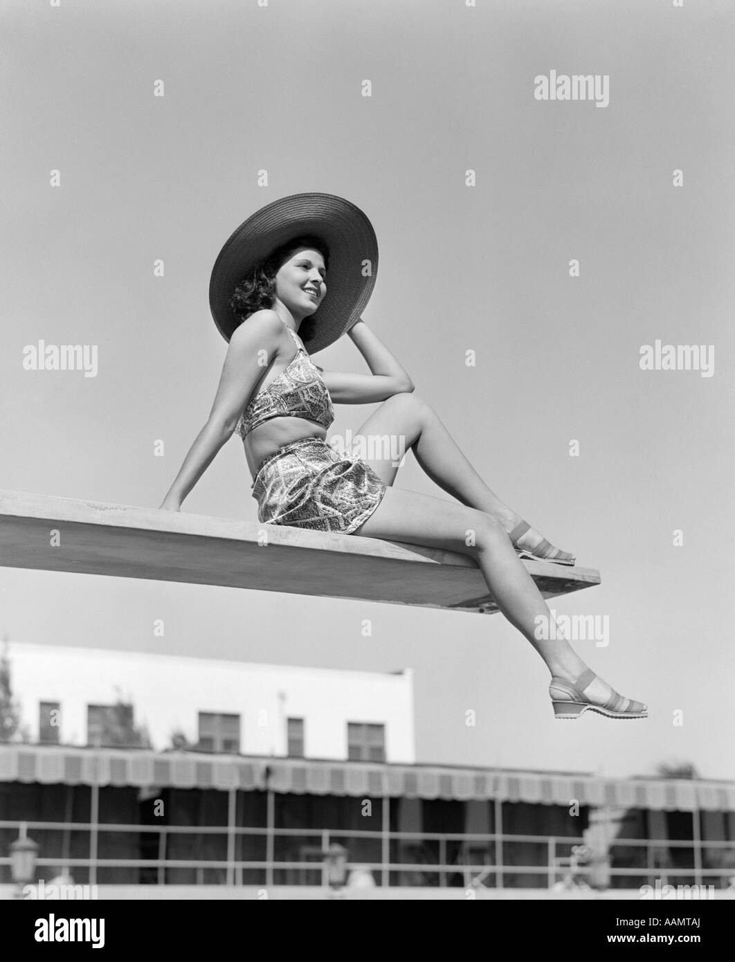 1930s donna che indossa HAT seduti vicino al bordo della scheda di immersioni Foto Stock