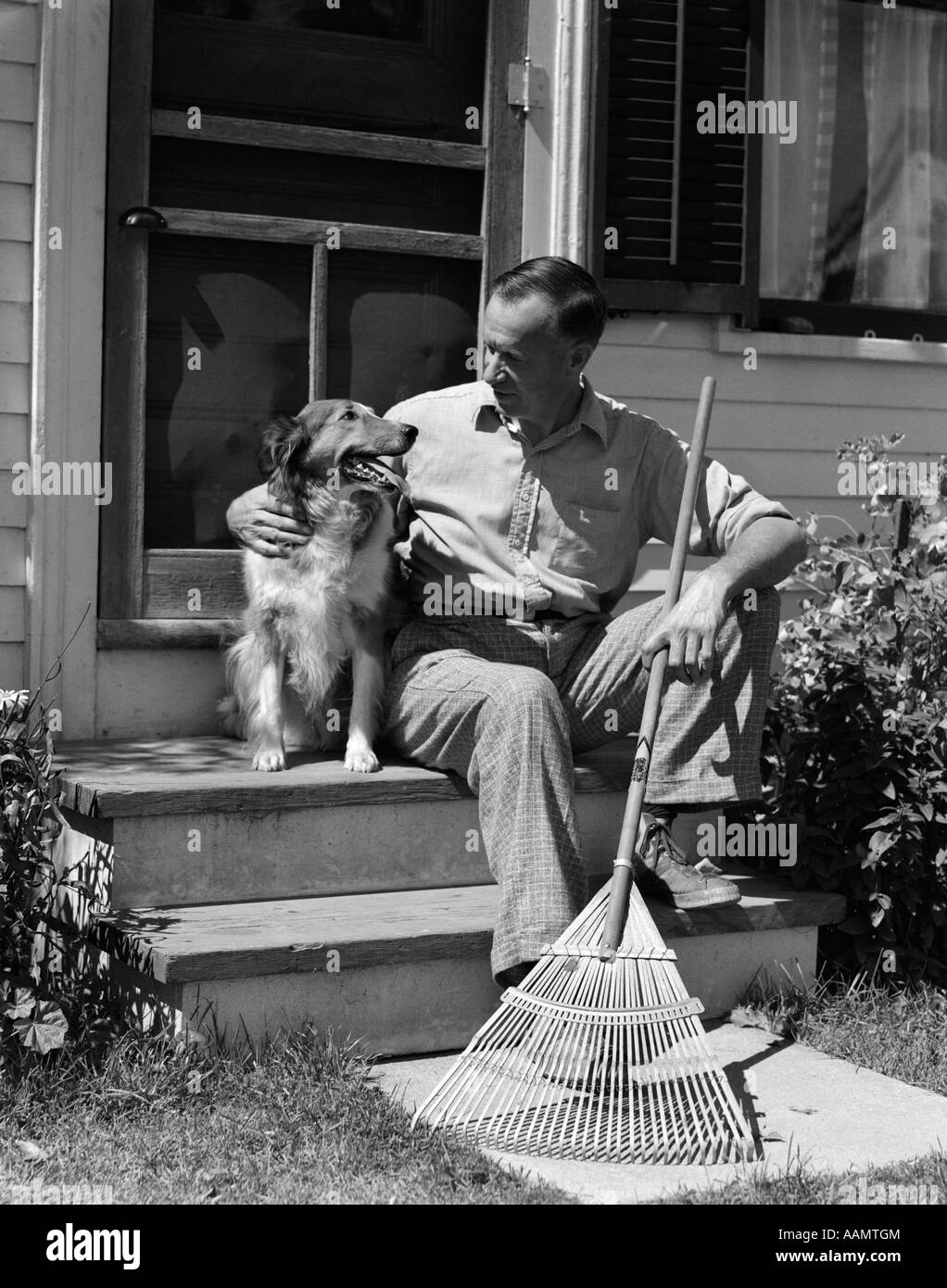 1930s 1940s uomo seduto sulle scale AZIENDA PETTING RAKE CANE Foto Stock