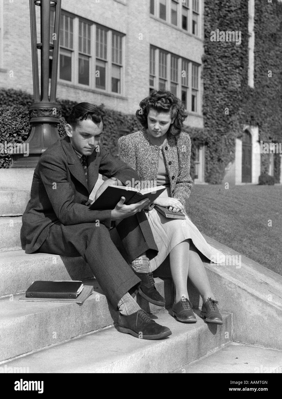 1940s 1930 maschile e femminile studente universitario che studia al di fuori del campus passi Foto Stock