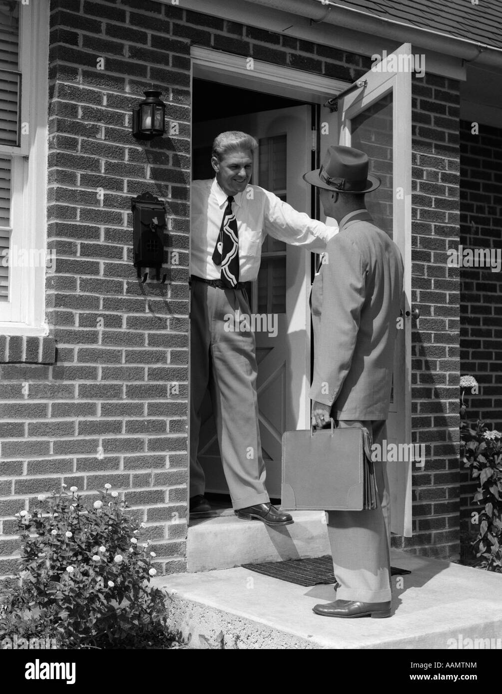 Anni Cinquanta VENDITORE A PARLARE CON L'uomo davanti alla porta di casa Foto Stock