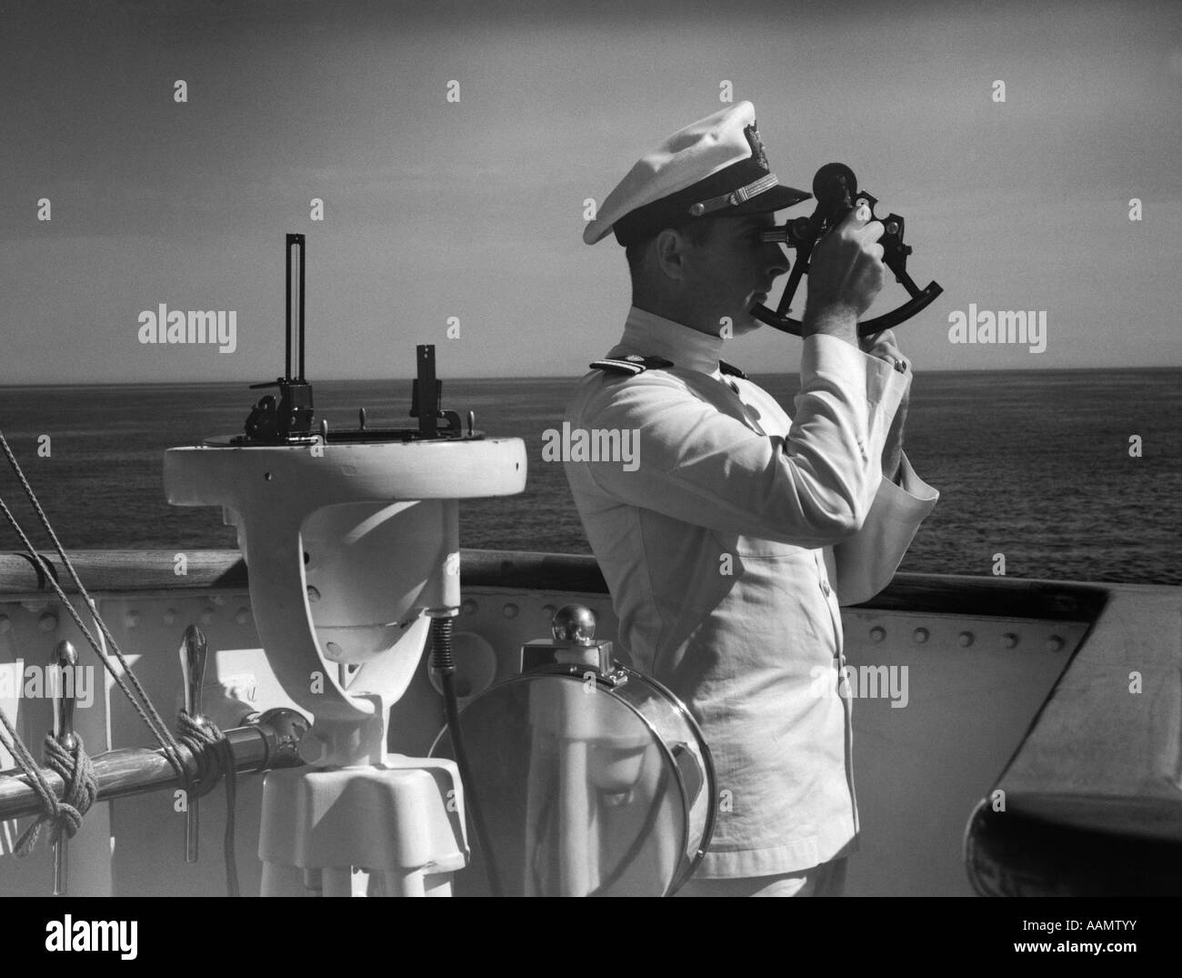 1940s uomo SAILOR CAPITANO OFFICER UTILIZZANDO SEXTANT sul ponte della nave Foto Stock