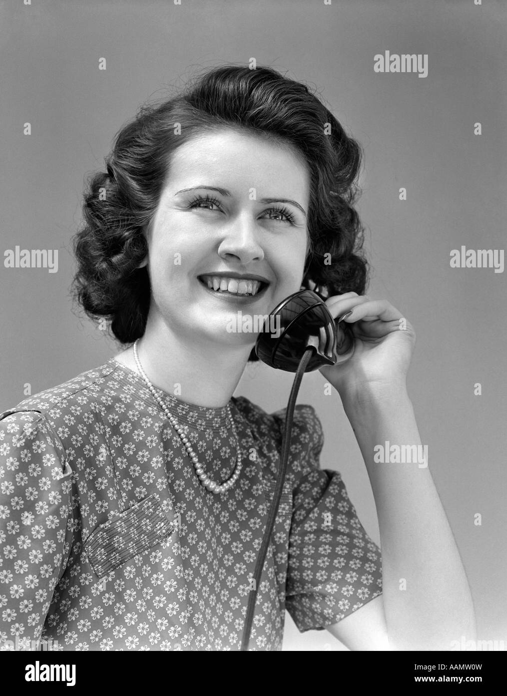 1940s sorridente BRUNETTE donna parlando al telefono alla ricerca fino Foto Stock